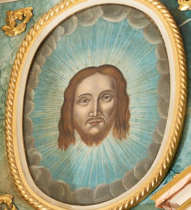 Zdjęcie nr 5: Ołtarz przyścienny, architektoniczny, jednoosiowy, jednokondygnacyjny ze zwieńczeniem. Mensa prostopadłościenna, w antepedium prostokątna płycina, w której umieszczony jest kurdyban, wytłaczany, barwiony i złocony z dekoracją ornamentalną składającą się z karbowanych taśm i motywów zwierzęcych oraz roślinnych. Retabulum ustawione na wysokim, dwustrefowym cokole, zamkniętym wyłamanym i profilowanym gzymsem. Predella ołtarza dekorowana owalnym, poziomym kartuszem ujętym ażurowymi, splecionymi liśćmi bujnego akantu i karbowanej wstęgi. Nastawa ołtarzowa flankowana parą filarów i kolumn ustawionych na tle pilastrów. Trzony kolumn do jednej trzeciej wysokości spiralnie skręcone, powyżej gładkie z grawerowaną wicią winorośli; trzony pilastrów do jednej trzeciej wysokości kanelowane, powyżej oplecione ukośnie wieńcem wawrzynu; kapitele podpór korynckie. Podpory wspierają wyłamane belkowanie, przerwane nad częścią środkową, zamknięte wydatnym, profilowanym gzymsem. W polu środkowym nastawy wnęka ze zdwojoną ramą w kształcie stojącego prostokąta, zamkniętego łukiem wklęsło-wypukłym z uskokami z obrazami „Przemienienie Pańskie” oraz „Ostatnia Wieczerza” na zasuwie. Na osi filarów w partii belkowania ustawione są pod kątem imposty, podtrzymywane przez płaskie, stylizowane muszle. Na tle filarów znajdują się figury: po lewej stronie Mojżesza, a po prawej Eliasza. Zwieńczenie w kształcie stojącego prostokąta, ujęte parą ukośnie dostawionych filarów, wspierających wyłamane belkowanie. Filary do jednej trzeciej wysokości zdobione ukośnym żłobkowaniem, powyżej kanelowane, kapitele korynckie. W polu środkowym owalny wizerunek twarzy Chrystusa. Na szczycie zwieńczenia oko Opatrzności wpisane w trójkąt, ujęte od dołu srebrzonymi obłokami i ukazane na tle promienistej glorii. Dekoracja ornamentalna: przednie ścianki cokołów dekorowane rozetami, po bokach cokołów owalne kartusze ujęte wydłużonymi liśćmi przeplecionymi karbowaną wstęgą; fryz dekorowany rozetami kwiatowymi; poniżej gzymsu ornament z liści akantu; po bokach zwieńczenia uszaki formowane z ażurowej wici roślinnej. Całość struktury ołtarza pokryta marmoryzacją zielono-niebieską; w dolnej części cokołu i w partiach belkowania w kolorze czerwono-różowym. Detale oraz profilowania pozłacane i posrebrzane. 