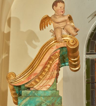 Zdjęcie nr 8: Nastawa ołtarzowa architektoniczna, jednoosiowa, jednokondygnacyjna. Ołtarz prostopadłościenny, drewniany, z drewnianą mensą na niskim cokole, flankowaną po bokach parą kanelowanych pilastrów o kapitelach jońskich. Antependium w formie płyciny marmoryzowanej na kolor różowy w kształcie leżącego prostokąta o owalnych narożach, ujęte w złoconą i wąską ramę. W polu płaskorzeźbione narzędzia Męki Pańskiej (krzyż, włócznia i korona cierniowa). 

Cokół nastawy zryzalitowany, wysoki, zdobiony płycinami z rozetami. Kondygnacja ujęta jest od wewnątrz parą pilastrów o kanelowanych trzonach, a od zewnątrz parą marmoryzowanych na zielono filarów i ustawioną przed nimi parą kolumn o kanelowanych i marmoryzowanych na różowo trzonach. Podpory ustawione są na bazach, mają kompozytowe kapitele i wspierają imposty oraz przerwane nad polem środkowym belkowanie, dekorowane profilowaniem i pasem kostkowania, a także przerwany, wolutowy przyczółek z parą aniołków. Nad środkiem belkowania nad dwóch niewielkich, spiętych spływach wolutowych ustawiona jest niewielkich rozmiarów rzeźbiona grupa przedstawiająca Boga Ojca po prawej i Jezusa Chrystusa po lewej stronie. Nad retabulum, nad wnęką okienną zawieszona jest gołębica Ducha Świętego w dużej promienistej glorii o promieniach, zebranych w wiązki nierównej długości. Retabulum po bokach ujęte jest uszami w formie ażurowej wici z ornamentu rocaille'owego.

W polu środkowym w szerokiej ramie w kształcie stojącego prostokąta, zamkniętego łukiem wklęsło-wypukłym z uskokami umieszczony jest obraz św. Mikołaja oraz św. Barbary na zasuwie. W zwieńczeniu ramy po bokach usadzona jest para aniołków. Poniżej obrazu fantazyjna, architektoniczna oprawa z umieszczonym w polu obrazem św. Teresy z Lisieux. Oprawa w formie niewielkiej, płaskiej aediculi, ustawionej na niskim cokole, flankowanej dwoma pilastrami, zamkniętej łukiem nadwieszonym, na szczycie którego niski cokolik na krucyfiks. Po bokach uszy o fantazyjnym wykroju, z wycięciem w górnej połowie, w dolnej zdobione kratką.

Struktura marmoryzowana jest w odcieniu niebieskim i jasnoróżowym; ornamentyka, profile, ramy i kanelury na pilastrach są złocone.