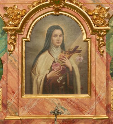 Zdjęcie nr 3: Nastawa ołtarzowa architektoniczna, jednoosiowa, jednokondygnacyjna. Ołtarz prostopadłościenny, drewniany, z drewnianą mensą na niskim cokole, flankowaną po bokach parą kanelowanych pilastrów o kapitelach jońskich. Antependium w formie płyciny marmoryzowanej na kolor różowy w kształcie leżącego prostokąta o owalnych narożach, ujęte w złoconą i wąską ramę. W polu płaskorzeźbione narzędzia Męki Pańskiej (krzyż, włócznia i korona cierniowa). 

Cokół nastawy zryzalitowany, wysoki, zdobiony płycinami z rozetami. Kondygnacja ujęta jest od wewnątrz parą pilastrów o kanelowanych trzonach, a od zewnątrz parą marmoryzowanych na zielono filarów i ustawioną przed nimi parą kolumn o kanelowanych i marmoryzowanych na różowo trzonach. Podpory ustawione są na bazach, mają kompozytowe kapitele i wspierają imposty oraz przerwane nad polem środkowym belkowanie, dekorowane profilowaniem i pasem kostkowania, a także przerwany, wolutowy przyczółek z parą aniołków. Nad środkiem belkowania nad dwóch niewielkich, spiętych spływach wolutowych ustawiona jest niewielkich rozmiarów rzeźbiona grupa przedstawiająca Boga Ojca po prawej i Jezusa Chrystusa po lewej stronie. Nad retabulum, nad wnęką okienną zawieszona jest gołębica Ducha Świętego w dużej promienistej glorii o promieniach, zebranych w wiązki nierównej długości. Retabulum po bokach ujęte jest uszami w formie ażurowej wici z ornamentu rocaille&#039;owego.

W polu środkowym w szerokiej ramie w kształcie stojącego prostokąta, zamkniętego łukiem wklęsło-wypukłym z uskokami umieszczony jest obraz św. Mikołaja oraz św. Barbary na zasuwie. W zwieńczeniu ramy po bokach usadzona jest para aniołków. Poniżej obrazu fantazyjna, architektoniczna oprawa z umieszczonym w polu obrazem św. Teresy z Lisieux. Oprawa w formie niewielkiej, płaskiej aediculi, ustawionej na niskim cokole, flankowanej dwoma pilastrami, zamkniętej łukiem nadwieszonym, na szczycie którego niski cokolik na krucyfiks. Po bokach uszy o fantazyjnym wykroju, z wycięciem w górnej połowie, w dolnej zdobione kratką.

Struktura marmoryzowana jest w odcieniu niebieskim i jasnoróżowym; ornamentyka, profile, ramy i kanelury na pilastrach są złocone.