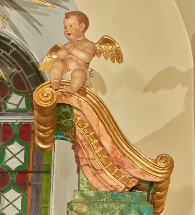 Zdjęcie nr 9: Nastawa ołtarzowa architektoniczna, jednoosiowa, jednokondygnacyjna. Ołtarz prostopadłościenny, drewniany, z drewnianą mensą na niskim cokole, flankowaną po bokach parą kanelowanych pilastrów o kapitelach jońskich. Antependium w formie płyciny marmoryzowanej na kolor różowy w kształcie leżącego prostokąta o owalnych narożach, ujęte w złoconą i wąską ramę. W polu płaskorzeźbione narzędzia Męki Pańskiej (krzyż, włócznia i korona cierniowa). 

Cokół nastawy zryzalitowany, wysoki, zdobiony płycinami z rozetami. Kondygnacja ujęta jest od wewnątrz parą pilastrów o kanelowanych trzonach, a od zewnątrz parą marmoryzowanych na zielono filarów i ustawioną przed nimi parą kolumn o kanelowanych i marmoryzowanych na różowo trzonach. Podpory ustawione są na bazach, mają kompozytowe kapitele i wspierają imposty oraz przerwane nad polem środkowym belkowanie, dekorowane profilowaniem i pasem kostkowania, a także przerwany, wolutowy przyczółek z parą aniołków. Nad środkiem belkowania nad dwóch niewielkich, spiętych spływach wolutowych ustawiona jest niewielkich rozmiarów rzeźbiona grupa przedstawiająca Boga Ojca po prawej i Jezusa Chrystusa po lewej stronie. Nad retabulum, nad wnęką okienną zawieszona jest gołębica Ducha Świętego w dużej promienistej glorii o promieniach, zebranych w wiązki nierównej długości. Retabulum po bokach ujęte jest uszami w formie ażurowej wici z ornamentu rocaille'owego.

W polu środkowym w szerokiej ramie w kształcie stojącego prostokąta, zamkniętego łukiem wklęsło-wypukłym z uskokami umieszczony jest obraz św. Mikołaja oraz św. Barbary na zasuwie. W zwieńczeniu ramy po bokach usadzona jest para aniołków. Poniżej obrazu fantazyjna, architektoniczna oprawa z umieszczonym w polu obrazem św. Teresy z Lisieux. Oprawa w formie niewielkiej, płaskiej aediculi, ustawionej na niskim cokole, flankowanej dwoma pilastrami, zamkniętej łukiem nadwieszonym, na szczycie którego niski cokolik na krucyfiks. Po bokach uszy o fantazyjnym wykroju, z wycięciem w górnej połowie, w dolnej zdobione kratką.

Struktura marmoryzowana jest w odcieniu niebieskim i jasnoróżowym; ornamentyka, profile, ramy i kanelury na pilastrach są złocone.