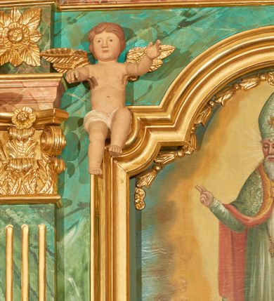 Zdjęcie nr 10: Nastawa ołtarzowa architektoniczna, jednoosiowa, jednokondygnacyjna. Ołtarz prostopadłościenny, drewniany, z drewnianą mensą na niskim cokole, flankowaną po bokach parą kanelowanych pilastrów o kapitelach jońskich. Antependium w formie płyciny marmoryzowanej na kolor różowy w kształcie leżącego prostokąta o owalnych narożach, ujęte w złoconą i wąską ramę. W polu płaskorzeźbione narzędzia Męki Pańskiej (krzyż, włócznia i korona cierniowa). 

Cokół nastawy zryzalitowany, wysoki, zdobiony płycinami z rozetami. Kondygnacja ujęta jest od wewnątrz parą pilastrów o kanelowanych trzonach, a od zewnątrz parą marmoryzowanych na zielono filarów i ustawioną przed nimi parą kolumn o kanelowanych i marmoryzowanych na różowo trzonach. Podpory ustawione są na bazach, mają kompozytowe kapitele i wspierają imposty oraz przerwane nad polem środkowym belkowanie, dekorowane profilowaniem i pasem kostkowania, a także przerwany, wolutowy przyczółek z parą aniołków. Nad środkiem belkowania nad dwóch niewielkich, spiętych spływach wolutowych ustawiona jest niewielkich rozmiarów rzeźbiona grupa przedstawiająca Boga Ojca po prawej i Jezusa Chrystusa po lewej stronie. Nad retabulum, nad wnęką okienną zawieszona jest gołębica Ducha Świętego w dużej promienistej glorii o promieniach, zebranych w wiązki nierównej długości. Retabulum po bokach ujęte jest uszami w formie ażurowej wici z ornamentu rocaille'owego.

W polu środkowym w szerokiej ramie w kształcie stojącego prostokąta, zamkniętego łukiem wklęsło-wypukłym z uskokami umieszczony jest obraz św. Mikołaja oraz św. Barbary na zasuwie. W zwieńczeniu ramy po bokach usadzona jest para aniołków. Poniżej obrazu fantazyjna, architektoniczna oprawa z umieszczonym w polu obrazem św. Teresy z Lisieux. Oprawa w formie niewielkiej, płaskiej aediculi, ustawionej na niskim cokole, flankowanej dwoma pilastrami, zamkniętej łukiem nadwieszonym, na szczycie którego niski cokolik na krucyfiks. Po bokach uszy o fantazyjnym wykroju, z wycięciem w górnej połowie, w dolnej zdobione kratką.

Struktura marmoryzowana jest w odcieniu niebieskim i jasnoróżowym; ornamentyka, profile, ramy i kanelury na pilastrach są złocone.