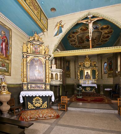 Zdjęcie nr 8: Kościół pomocniczny pw. Wniebowzięcia Najświętszej Marii Panny w Woli Radziszowskiej to niewielkich rozmiarów, orientowana, jednonawowa budowla drewniana, konstrukcji zrębowej, z wieżą w słup. Prezbiterium jest zamknięte wielobocznie, nieco wyższa i szersza nawa ma rzut prostokąta zbliżonego do kwadratu. Do prezbiterium od strony północnej przylega zakrystia, od wschodniej Ogrójec, przy nawie od południa umieszczona została niewielka, prostokątna kruchta. Od zachodu do budowli dostawiona jest czworoboczna wieża o pochyłych ścianach, z podwieszoną izbicą z czworobocznymi występami na przekątnikach; hełm ostrosłupowy z czterema wieżyczkami na występach. W przyziemiu wieży znajduje się kruchta, a dookoła wieży szalowane soboty. Wewnątrz świątyni stropy; w nawie z zaskrzynieniami. Otwór tęczowy ma kształt ostrołuku, belka jest profilowana, na niej umieszczony jest krucyfiks o charakterze późnogotyckim. Chór muzyczny w zachodniej części nawy jest drewniany, wsparty na dwóch kolumnach. Okna nawy i prezbiterium są głównie prostokątne zamknięte półkoliście; z witrażami (z wyjątkiem okna za ołtarzem głównym); ponadto budowlę doświetlają niewielkie okienka prostokątne. Do świątyni prowadzi dwoje drzwi ostrołukowych, trzecie od strony zachodniej przerobiono w 1933 roku. Dachy kościoła są kryte gontem, ponad nawą i kruchtą południową dwuspadowe, nad zakrystią jednospadowy, nad prezbiterium wielopołaciowy. Wieżyczka na sygnaturkę o formach barokowych z glorietą, cebulastym hełmem zwieńczonym kulą oraz krzyżem; kryta blachą. Świątynia usytuowana jest na niewielkiej działce, wydzielonej ogrodzeniem z drewnianych bali, krytym gontem. Bramy wiodące na posesję umieszczono od zachodu oraz w południowo-wschodnim narożniku działki.