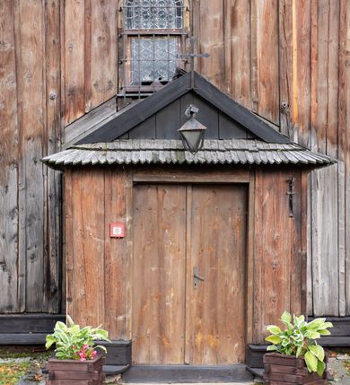 Zdjęcie nr 38: Kościół pomocniczny pw. Wniebowzięcia Najświętszej Marii Panny w Woli Radziszowskiej to niewielkich rozmiarów, orientowana, jednonawowa budowla drewniana, konstrukcji zrębowej, z wieżą w słup. Prezbiterium jest zamknięte wielobocznie, nieco wyższa i szersza nawa ma rzut prostokąta zbliżonego do kwadratu. Do prezbiterium od strony północnej przylega zakrystia, od wschodniej Ogrójec, przy nawie od południa umieszczona została niewielka, prostokątna kruchta. Od zachodu do budowli dostawiona jest czworoboczna wieża o pochyłych ścianach, z podwieszoną izbicą z czworobocznymi występami na przekątnikach; hełm ostrosłupowy z czterema wieżyczkami na występach. W przyziemiu wieży znajduje się kruchta, a dookoła wieży szalowane soboty. Wewnątrz świątyni stropy; w nawie z zaskrzynieniami. Otwór tęczowy ma kształt ostrołuku, belka jest profilowana, na niej umieszczony jest krucyfiks o charakterze późnogotyckim. Chór muzyczny w zachodniej części nawy jest drewniany, wsparty na dwóch kolumnach. Okna nawy i prezbiterium są głównie prostokątne zamknięte półkoliście; z witrażami (z wyjątkiem okna za ołtarzem głównym); ponadto budowlę doświetlają niewielkie okienka prostokątne. Do świątyni prowadzi dwoje drzwi ostrołukowych, trzecie od strony zachodniej przerobiono w 1933 roku. Dachy kościoła są kryte gontem, ponad nawą i kruchtą południową dwuspadowe, nad zakrystią jednospadowy, nad prezbiterium wielopołaciowy. Wieżyczka na sygnaturkę o formach barokowych z glorietą, cebulastym hełmem zwieńczonym kulą oraz krzyżem; kryta blachą. Świątynia usytuowana jest na niewielkiej działce, wydzielonej ogrodzeniem z drewnianych bali, krytym gontem. Bramy wiodące na posesję umieszczono od zachodu oraz w południowo-wschodnim narożniku działki.