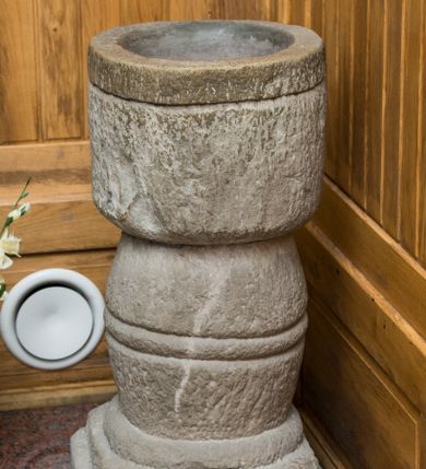 Zdjęcie nr 1: Kropielnica stojąca na dwustrefowej podstawie na rzucie kwadratu. Trzon o beczkowatym kształcie, u dołu ujęty ćwierćwałkiem, pośrodku zdobiony dwoma równoległymi, rytymi liniami. Czara o zarysie koła z rytą linią poniżej wylewu. Powierzchnia kropielnicy jest fakturowana, kolor naturalny. 