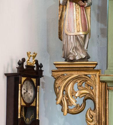 Zdjęcie nr 8: Ołtarz przyścienny, architektoniczny, jednoosiowy, dwukondygnacyjny ze zwieńczeniem. Mensa prostopadłościenna z kamiennym blatem z portatylem, boki mensy z polerowanych płyt kamiennych. Dekoracja antepedium współczesna z aplikowanych metalowych motywów kielicha z hostią i kłosów. Retabulum ujęte parą kolumn korynckich ustawionych na schodkowych cokołach podzielonych gzymsem na dwie strefy. Podpory wspierają belkowanie przerwane w partii architrawu i fryzu nad polem środkowym. Belkowanie zamknięte wydatnym, profilowanym, wyłamanym gzymsem. Powyżej, na osiach zewnętrznych kolumn ustawione odcinki falistego przyczółka o wolutowo skręconych końcach. W polu środkowym wnęka w kształcie stojącego prostokąta zamknięta łukiem półkolistym, na kluczu łuku rzeźba gołębicy Ducha Świętego. Wewnątrz prostokątny otwór na obraz – wymiennie przedstawienie św. Marii Magdaleny pod krzyżem, „Noli me tangere” oraz wizerunek Marki Boskiej Myślenickiej. Zwieńczenie ujęte parą pilastrów, zamknięte trójbocznie z ośmiobocznym polem środkowym. Wnęka pola środkowego retabulum i zwieńczenia ujęta szeroką, ażurową ramą formowaną z wolutowo skręconych liści akantu. W zwieńczeniu obraz przedstawiający Boga Ojca. Ściany cokołów dekorowane płycinami wypełnionymi skręconymi liśćmi akantu. Poniżej gzymsu zamykającego retabulum ażurowy ornament akantowy. U góry boki nastawy ujęte ażurowymi uszakami formowanymi ze skręconych liści akantu, poniżej tworzących parę konsolek. Zwieńczenie ujęte uszakami formowanymi z ornamentu małżowinowo-chrząstowego. Na gzymsie zwieńczenia rzeźbione wazony i czworoliść z monogramem IHS na tle glorii promienistej. Na konsolkach po bokach retabulum ustawione figury św. Wojciecha i świętego z księgą po lewej oraz św. Stanisława i świętego z pastorałem po prawej stronie. Na odcinkach przyczółka figury uskrzydlonych aniołów. Całość struktury retabulum malowana w kolorze jasnozielonym. Detal architektoniczny, profilowania i ornamentyka złocone. 