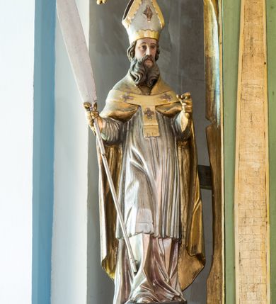 Zdjęcie nr 13: Ołtarz przyścienny, architektoniczny, jednoosiowy, dwukondygnacyjny ze zwieńczeniem. Mensa prostopadłościenna z kamiennym blatem z portatylem, boki mensy z polerowanych płyt kamiennych. Dekoracja antepedium współczesna z aplikowanych metalowych motywów kielicha z hostią i kłosów. Retabulum ujęte parą kolumn korynckich ustawionych na schodkowych cokołach podzielonych gzymsem na dwie strefy. Podpory wspierają belkowanie przerwane w partii architrawu i fryzu nad polem środkowym. Belkowanie zamknięte wydatnym, profilowanym, wyłamanym gzymsem. Powyżej, na osiach zewnętrznych kolumn ustawione odcinki falistego przyczółka o wolutowo skręconych końcach. W polu środkowym wnęka w kształcie stojącego prostokąta zamknięta łukiem półkolistym, na kluczu łuku rzeźba gołębicy Ducha Świętego. Wewnątrz prostokątny otwór na obraz – wymiennie przedstawienie św. Marii Magdaleny pod krzyżem, „Noli me tangere” oraz wizerunek Marki Boskiej Myślenickiej. Zwieńczenie ujęte parą pilastrów, zamknięte trójbocznie z ośmiobocznym polem środkowym. Wnęka pola środkowego retabulum i zwieńczenia ujęta szeroką, ażurową ramą formowaną z wolutowo skręconych liści akantu. W zwieńczeniu obraz przedstawiający Boga Ojca. Ściany cokołów dekorowane płycinami wypełnionymi skręconymi liśćmi akantu. Poniżej gzymsu zamykającego retabulum ażurowy ornament akantowy. U góry boki nastawy ujęte ażurowymi uszakami formowanymi ze skręconych liści akantu, poniżej tworzących parę konsolek. Zwieńczenie ujęte uszakami formowanymi z ornamentu małżowinowo-chrząstowego. Na gzymsie zwieńczenia rzeźbione wazony i czworoliść z monogramem IHS na tle glorii promienistej. Na konsolkach po bokach retabulum ustawione figury św. Wojciecha i świętego z księgą po lewej oraz św. Stanisława i świętego z pastorałem po prawej stronie. Na odcinkach przyczółka figury uskrzydlonych aniołów. Całość struktury retabulum malowana w kolorze jasnozielonym. Detal architektoniczny, profilowania i ornamentyka złocone. 