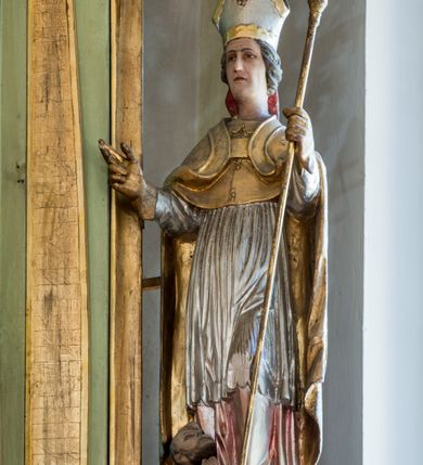 Zdjęcie nr 14: Ołtarz przyścienny, architektoniczny, jednoosiowy, dwukondygnacyjny ze zwieńczeniem. Mensa prostopadłościenna z kamiennym blatem z portatylem, boki mensy z polerowanych płyt kamiennych. Dekoracja antepedium współczesna z aplikowanych metalowych motywów kielicha z hostią i kłosów. Retabulum ujęte parą kolumn korynckich ustawionych na schodkowych cokołach podzielonych gzymsem na dwie strefy. Podpory wspierają belkowanie przerwane w partii architrawu i fryzu nad polem środkowym. Belkowanie zamknięte wydatnym, profilowanym, wyłamanym gzymsem. Powyżej, na osiach zewnętrznych kolumn ustawione odcinki falistego przyczółka o wolutowo skręconych końcach. W polu środkowym wnęka w kształcie stojącego prostokąta zamknięta łukiem półkolistym, na kluczu łuku rzeźba gołębicy Ducha Świętego. Wewnątrz prostokątny otwór na obraz – wymiennie przedstawienie św. Marii Magdaleny pod krzyżem, „Noli me tangere” oraz wizerunek Marki Boskiej Myślenickiej. Zwieńczenie ujęte parą pilastrów, zamknięte trójbocznie z ośmiobocznym polem środkowym. Wnęka pola środkowego retabulum i zwieńczenia ujęta szeroką, ażurową ramą formowaną z wolutowo skręconych liści akantu. W zwieńczeniu obraz przedstawiający Boga Ojca. Ściany cokołów dekorowane płycinami wypełnionymi skręconymi liśćmi akantu. Poniżej gzymsu zamykającego retabulum ażurowy ornament akantowy. U góry boki nastawy ujęte ażurowymi uszakami formowanymi ze skręconych liści akantu, poniżej tworzących parę konsolek. Zwieńczenie ujęte uszakami formowanymi z ornamentu małżowinowo-chrząstowego. Na gzymsie zwieńczenia rzeźbione wazony i czworoliść z monogramem IHS na tle glorii promienistej. Na konsolkach po bokach retabulum ustawione figury św. Wojciecha i świętego z księgą po lewej oraz św. Stanisława i świętego z pastorałem po prawej stronie. Na odcinkach przyczółka figury uskrzydlonych aniołów. Całość struktury retabulum malowana w kolorze jasnozielonym. Detal architektoniczny, profilowania i ornamentyka złocone. 