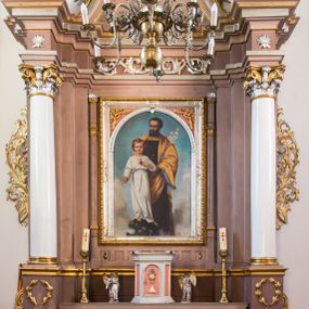 Zdjęcie nr 1: Ołtarz przyścienny, architektoniczny, na cokole. Mensa w typie sarkofagowym; antepedium dekorowane romboidalną plakietą z rozetą na tle liści. Na mensie tabernakulum na rzucie zbliżonym do kwadratu o ściętych przednich narożach, na profilowanej podstawie. Na froncie drzwi w kształcie stojącego prostokąta zamkniętego łukiem półkolistym dekorowane kielichem z hostią; na skośnych ściankach prostokątne płyciny. Zwieńczenie w formie gzymsu. Obok tabernakulum stoją niewielkie, całopostaciowe figurki aniołów – po lewej stronie skłaniającego się w modlitwie, po prawej wyciągającego ręce przed siebie. Nastawa ołtarzowa jednoosiowa, jednokondygnacyjna ze zwieńczeniem. Oś środkowa jest flankowana parą kolumn o kapitelach kompozytowych, ustawionych przed licem ołtarza, na tle zwielokrotnionych pilastrów. Cokoły kolumn dekorowane wieńcami laurowymi. Podpory dźwigają pełne, wyłamane wielokrotnie belkowanie oraz odpowiadające ich ułożeniu cokoły, na których klęczy para modlących się aniołów; na środku, na fryzie belkowania wić roślinna. W polu głównym, we wnęce w kształcie stojącego prostokąta obraz w kształcie takiegoż prostokąta zamkniętego łukiem półkolistym z przedstawieniem św. Józefa z małym Jezusem ujętego ramą z dekoracją w przyłuczach. 
Kondygnację ujmują ażurowe uszaki utworzone z suchej wici akantowej połączonej z rozwiniętymi kwiatkami. Zwieńczenie o kształcie wklęsło-wypukłym, zamknięte od góry łukiem nadwieszonym utworzonym z wolut spiętych płomienistym rocaille’em. Wypełnia je mały owalny obraz z przedstawieniem św. Maksymiliana Kolbe w profilowanej ramie. Spływy zwieńczenia dekorują liście palmowe. 
Struktura polichromowana na kolor jasnobrązowy ze złoconą i srebrzoną ornamentyką oraz detalami architektonicznymi; kolumny białe; tabernakulum białe z różowymi płycinami i złoconymi detalami. 
