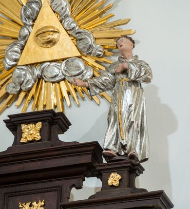 Zdjęcie nr 2: Ołtarz architektoniczny, przyścienny, jednoosiowy, dwukondygnacyjny ze zwieńczeniem. Nastawa umieszczona jest na skrzyniowej mensie. Jej antepedium dekoruje ciemnoróżowa tkanina zdobiona wzorem zwiniętej wici roślinnej. Cokół jest wypełniony w centrum prostokątną płyciną, a na osiach zewnętrznych plakietami ornamentalnymi utworzonymi z motywów roślinnych z dziecięcymi główkami. Nastawa flankowana ustawionymi na wysuniętych partiach cokołu kolumnami dźwigającymi fragmenty pełnego belkowania, które podtrzymują partie urwanego przyczółka. W polu centralnym nisza w kształcie stojącego prostokąta z uskokiem, ponad którym gzyms i łuk półokrągły. W niszy umieszczono ujęty złoconą, ażurową ramą obraz z wizerunkiem św. Andrzeja z 1684 roku (przemalowany) wymiennie z obrazem Najświętszego Serca Jezusa. Powyżej obrazu, w łuku, plakieta dekoracyjna; na kluczu łuku owalne pole ujęte liśćmi. Druga kondygnacja w kształcie leżącego prostokąta z uszakami jest zwieńczona trzema postumentami, z których każdy dźwiga fragment gzymsu podtrzymującego cokół. Na zewnętrznych ustawiono postacie św. Jana Ewangelisty z lewej strony i być może św. Dominika z prawej. Kondygnację ujmują uszaki utworzone z suchej wici akantowej, pole wypełnia owalny obraz z popiersiem Matki Boskiej Niepokalanej. Nastawę wieńczy umieszczone na ścianie oko Opatrzności pośród chmur i w glorii promienistej. 