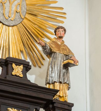 Zdjęcie nr 6: Ołtarz architektoniczny, przyścienny, jednoosiowy, dwukondygnacyjny ze zwieńczeniem. Nastawa umieszczona jest na skrzyniowej mensie, której antepedium dekoruje ciemnoróżowa tkanina zdobiona wzorem zwiniętej wici roślinnej. Cokół jest wypełniony w centrum prostokątną płyciną, a na osiach zewnętrznych plakietami ornamentalnymi utworzonymi z motywów roślinnych z dziecięcymi główkami. Nastawa flankowana ustawionymi na wysuniętych partiach cokołu kolumnami dźwigającymi fragmenty pełnego belkowania, które podtrzymują partie urwanego przyczółka. W polu centralnym nisza w kształcie stojącego prostokąta z uskokiem, ponad którym gzyms i łuk półokrągły. W niszy umieszczono ujęty złoconą, ażurową ramą obraz z wizerunkiem Matki Boskiej Częstochowskiej. Powyżej obrazu, w łuku, plakieta dekoracyjna. Druga kondygnacja w kształcie leżącego prostokąta z uszakami jest zwieńczona trzema postumentami, z których wszystkie dźwigają fragmenty gzymsu podtrzymującego cokoły. Na zewnętrznych ustawiono postacie niezidentyfikowanych świętych. Kondygnację ujmują uszaki utworzone z suchej wici akantowej, pole wypełnia owalny obraz z popiersiem błogosławiącego Jezusa. Nastawę wieńczy umieszczony na ścianie monogram maryjny ujęty w kształt kropi i umieszczony na tle glorii promienistej. 
Struktura polichromowana na kolor ciemnobrązowy ze złoconymi kolumnami oraz złoconą i srebrzoną ornamentyką oraz detalami architektonicznymi.
