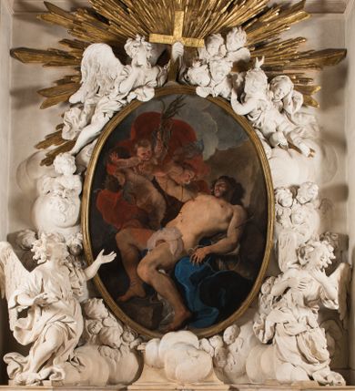 Zdjęcie nr 1: Na niskim postumencie o krawędzi przedniej wyciętej linią falistą osadzony ołtarz w kształcie wybrzuszonej górą tumby. Jego antepedium wypełnione marmoryzacją (w technice skaliola) z krzyżującymi się palmami męczeństwa. Po bokach ołtarza dwa ukośnie dostawione postumenty, na których dwie figury aniołów flankujących owalny obraz w złoconej ramie z przedstawieniem męczeństwa św. Sebastiana. Malowidło jest obwiedzione dekoracją sztukatorską w formie obłoków z główkami lub postaciami aniołów, zwieńczone krzyżem i glorią promienistą. Anioły klęczące na postumentach ukazane są w poruszonych pozach, w obficie drapowanych szatach, tworzących grube, mięsiste poły. Anioł po lewej stronie ma głowę zwróconą w kierunku obrazu, a ręce rozkłada na boki, anioł po przeciwnej stronie głowę odwraca w odwrotnym niż obraz kierunku, a jego ręce są uniesione na wysokość klatki piersiowej i skierowane do środka. Nad obrazem anioł po lewej stronie niemalże leży na ramie obrazu, w lewej ręce trzyma krzyż, prawą lekko unosi. Ubrany jest w miękko drapowane szaty, odsłaniające dolną część jego prawej nogi. Duże skrzydła o gęstych piórach rozłożone są niesymetrycznie. Po przeciwnej stronie ukazane putta i główki modelowanych sumarycznie, pulchnych aniołków. Dolne partie wykonane z kamienia, marmoryzowane w jasnych kolorach z czarnym polem antepedium wypełnionym jasnozielonymi palmami męczeństwa. Partie rzeźbiarskie białe, rama obrazu, krzyż i gloria złocone. 

