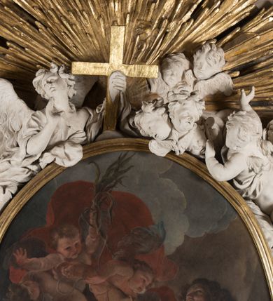 Zdjęcie nr 21: Na niskim postumencie o krawędzi przedniej wyciętej linią falistą osadzony ołtarz w kształcie wybrzuszonej górą tumby. Jego antepedium wypełnione marmoryzacją (w technice skaliola) z krzyżującymi się palmami męczeństwa. Po bokach ołtarza dwa ukośnie dostawione postumenty, na których dwie figury aniołów flankujących owalny obraz w złoconej ramie z przedstawieniem męczeństwa św. Sebastiana. Malowidło jest obwiedzione dekoracją sztukatorską w formie obłoków z główkami lub postaciami aniołów, zwieńczone krzyżem i glorią promienistą. Anioły klęczące na postumentach ukazane są w poruszonych pozach, w obficie drapowanych szatach, tworzących grube, mięsiste poły. Anioł po lewej stronie ma głowę zwróconą w kierunku obrazu, a ręce rozkłada na boki, anioł po przeciwnej stronie głowę odwraca w odwrotnym niż obraz kierunku, a jego ręce są uniesione na wysokość klatki piersiowej i skierowane do środka. Nad obrazem anioł po lewej stronie niemalże leży na ramie obrazu, w lewej ręce trzyma krzyż, prawą lekko unosi. Ubrany jest w miękko drapowane szaty, odsłaniające dolną część jego prawej nogi. Duże skrzydła o gęstych piórach rozłożone są niesymetrycznie. Po przeciwnej stronie ukazane putta i główki modelowanych sumarycznie, pulchnych aniołków. Dolne partie wykonane z kamienia, marmoryzowane w jasnych kolorach z czarnym polem antepedium wypełnionym jasnozielonymi palmami męczeństwa. Partie rzeźbiarskie białe, rama obrazu, krzyż i gloria złocone. 

