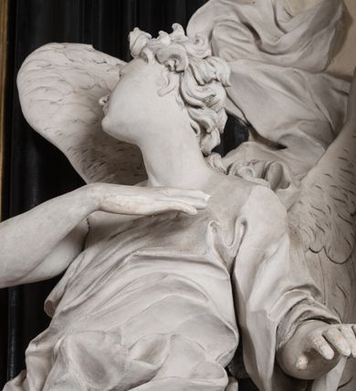 Zdjęcie nr 17: Na niskim postumencie, na rzucie prostokąta z łukiem nadwieszonym od przodu osadzony ołtarz prostopadłościenny. Antepedium marmoryzowane z owalnym polem i rytym przedstawieniem głowy św. Jana Chrzciciela na tacy spoczywającej na postumencie ze skrzyżowanymi szablą i krzyżem oraz banderolą z inskrypcją „ECCE AGNUS DEI”. Zasadniczą część ołtarza stanowi obraz w kształcie stojącego prostokąta w bogato profilowanej, szerokiej ramie, ujętej dwoma aniołami. Obaj stoją na skłębionych obłokach, ukazani frontalnie, w silnym kontrapoście. Ubrani są w przylegające do ich ciał szaty, modelowane swobodnie, silnie drapowane i marszczone. Anioł po lewej głowę zwraca w kierunku obrazu i unosi wysoko złożone w geście modlitwy ręce. Drugi anioł również zwraca się w kierunku obrazu, prawą rękę trzyma na piersi, lewą na wysokości bioder. Obaj mają rozłożyste skrzydła o gęstych piórach. Ramę wieńczy profilowany gzyms wyłamany półkoliście pośrodku z ukośnymi odcinkami na bokach o lekko wklęsłych krawędziach z podwieszonymi pod nie żłobkowanymi impostami, pod którymi unoszące je putta. Nad gzymsem pośrodku siedzi na obłoku z główkami aniołków anioł z rozłożystymi skrzydłami, trzymający w rękach banderolę z napisem „ECCE AGNUS DEI”. Po bokach gzymsu osadzone na nim obłoki z główkami aniołków. Ołtarz z wielobarwną marmoryzacją w dolnej części, czarną ramą i białą dekoracją rzeźbiarską.