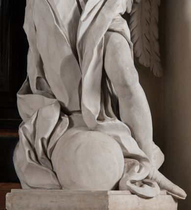 Zdjęcie nr 19: Na niskim postumencie, na rzucie prostokąta z łukiem nadwieszonym od przodu osadzony ołtarz prostopadłościenny. Antepedium marmoryzowane z owalnym polem i rytym przedstawieniem głowy św. Jana Chrzciciela na tacy spoczywającej na postumencie ze skrzyżowanymi szablą i krzyżem oraz banderolą z inskrypcją „ECCE AGNUS DEI”. Zasadniczą część ołtarza stanowi obraz w kształcie stojącego prostokąta w bogato profilowanej, szerokiej ramie, ujętej dwoma aniołami. Obaj stoją na skłębionych obłokach, ukazani frontalnie, w silnym kontrapoście. Ubrani są w przylegające do ich ciał szaty, modelowane swobodnie, silnie drapowane i marszczone. Anioł po lewej głowę zwraca w kierunku obrazu i unosi wysoko złożone w geście modlitwy ręce. Drugi anioł również zwraca się w kierunku obrazu, prawą rękę trzyma na piersi, lewą na wysokości bioder. Obaj mają rozłożyste skrzydła o gęstych piórach. Ramę wieńczy profilowany gzyms wyłamany półkoliście pośrodku z ukośnymi odcinkami na bokach o lekko wklęsłych krawędziach z podwieszonymi pod nie żłobkowanymi impostami, pod którymi unoszące je putta. Nad gzymsem pośrodku siedzi na obłoku z główkami aniołków anioł z rozłożystymi skrzydłami, trzymający w rękach banderolę z napisem „ECCE AGNUS DEI”. Po bokach gzymsu osadzone na nim obłoki z główkami aniołków. Ołtarz z wielobarwną marmoryzacją w dolnej części, czarną ramą i białą dekoracją rzeźbiarską.