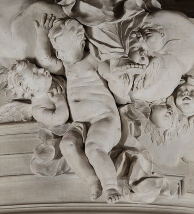 Zdjęcie nr 14: Na niewysokim stopniu prostopadłościenny ołtarz z antepedium, którego dekoracja wykonana w technice marmoryzacji (skaliola) w postaci owalnego pola z wyobrażeniem źródła życia wiecznego (dwa ptaki pijące wodę z fontanny) oraz pęków kwiatów. Nad ołtarzem nastawa z niemal pełnoplastyczną figurą Matki Boskiej Niepokalanej ujęta pilastrami i stojącymi przed nimi marmoryzowanymi kolumnami z kapitelami jońskimi podtrzymującymi szerokie belkowanie zwieńczone naczółkami. W środkowej części belkowania grupa rzeźbiarska z figurą Boga Ojca spoczywającego na obłokach trzymanych przez putta i anioły. Stojąca na obłokach i księżycu Matka Boska ukazana frontalnie, w kontrapoście, z rękami złożonymi do modlitwy. Jej twarz jest modelowana łagodnie, owalna, z długim nosem, otwartymi oczami. Nad głową wieniec z gwiazd. Ubrana jest w długą suknię i rozłożysty płaszcz o skłębionych połach, drapowanych plastycznie. Z tła wyłaniają się putta i uskrzydlone główki aniołów oraz promienie słońca. Postać Boga Ojca siedzącego na chmurach z rozwianymi szatami ukazana frontalnie. Prawą rękę wysuwa do przodu, w lewej trzyma berło. Ołtarz utrzymany w jasnej tonacji kolorystycznej, z elementami z czarnego marmuru i wielobarwnym antepedium w technice marmoryzacji. 