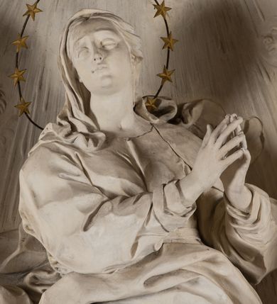 Zdjęcie nr 7: Na niewysokim stopniu prostopadłościenny ołtarz z antepedium, którego dekoracja wykonana w technice marmoryzacji (skaliola) w postaci owalnego pola z wyobrażeniem źródła życia wiecznego (dwa ptaki pijące wodę z fontanny) oraz pęków kwiatów. Nad ołtarzem nastawa z niemal pełnoplastyczną figurą Matki Boskiej Niepokalanej ujęta pilastrami i stojącymi przed nimi marmoryzowanymi kolumnami z kapitelami jońskimi podtrzymującymi szerokie belkowanie zwieńczone naczółkami. W środkowej części belkowania grupa rzeźbiarska z figurą Boga Ojca spoczywającego na obłokach trzymanych przez putta i anioły. Stojąca na obłokach i księżycu Matka Boska ukazana frontalnie, w kontrapoście, z rękami złożonymi do modlitwy. Jej twarz jest modelowana łagodnie, owalna, z długim nosem, otwartymi oczami. Nad głową wieniec z gwiazd. Ubrana jest w długą suknię i rozłożysty płaszcz o skłębionych połach, drapowanych plastycznie. Z tła wyłaniają się putta i uskrzydlone główki aniołów oraz promienie słońca. Postać Boga Ojca siedzącego na chmurach z rozwianymi szatami ukazana frontalnie. Prawą rękę wysuwa do przodu, w lewej trzyma berło. Ołtarz utrzymany w jasnej tonacji kolorystycznej, z elementami z czarnego marmuru i wielobarwnym antepedium w technice marmoryzacji. 