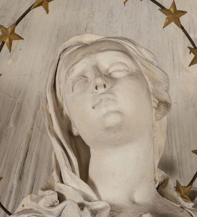 Zdjęcie nr 8: Na niewysokim stopniu prostopadłościenny ołtarz z antepedium, którego dekoracja wykonana w technice marmoryzacji (skaliola) w postaci owalnego pola z wyobrażeniem źródła życia wiecznego (dwa ptaki pijące wodę z fontanny) oraz pęków kwiatów. Nad ołtarzem nastawa z niemal pełnoplastyczną figurą Matki Boskiej Niepokalanej ujęta pilastrami i stojącymi przed nimi marmoryzowanymi kolumnami z kapitelami jońskimi podtrzymującymi szerokie belkowanie zwieńczone naczółkami. W środkowej części belkowania grupa rzeźbiarska z figurą Boga Ojca spoczywającego na obłokach trzymanych przez putta i anioły. Stojąca na obłokach i księżycu Matka Boska ukazana frontalnie, w kontrapoście, z rękami złożonymi do modlitwy. Jej twarz jest modelowana łagodnie, owalna, z długim nosem, otwartymi oczami. Nad głową wieniec z gwiazd. Ubrana jest w długą suknię i rozłożysty płaszcz o skłębionych połach, drapowanych plastycznie. Z tła wyłaniają się putta i uskrzydlone główki aniołów oraz promienie słońca. Postać Boga Ojca siedzącego na chmurach z rozwianymi szatami ukazana frontalnie. Prawą rękę wysuwa do przodu, w lewej trzyma berło. Ołtarz utrzymany w jasnej tonacji kolorystycznej, z elementami z czarnego marmuru i wielobarwnym antepedium w technice marmoryzacji. 