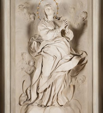 Zdjęcie nr 4: Na niewysokim stopniu prostopadłościenny ołtarz z antepedium, którego dekoracja wykonana w technice marmoryzacji (skaliola) w postaci owalnego pola z wyobrażeniem źródła życia wiecznego (dwa ptaki pijące wodę z fontanny) oraz pęków kwiatów. Nad ołtarzem nastawa z niemal pełnoplastyczną figurą Matki Boskiej Niepokalanej ujęta pilastrami i stojącymi przed nimi marmoryzowanymi kolumnami z kapitelami jońskimi podtrzymującymi szerokie belkowanie zwieńczone naczółkami. W środkowej części belkowania grupa rzeźbiarska z figurą Boga Ojca spoczywającego na obłokach trzymanych przez putta i anioły. Stojąca na obłokach i księżycu Matka Boska ukazana frontalnie, w kontrapoście, z rękami złożonymi do modlitwy. Jej twarz jest modelowana łagodnie, owalna, z długim nosem, otwartymi oczami. Nad głową wieniec z gwiazd. Ubrana jest w długą suknię i rozłożysty płaszcz o skłębionych połach, drapowanych plastycznie. Z tła wyłaniają się putta i uskrzydlone główki aniołów oraz promienie słońca. Postać Boga Ojca siedzącego na chmurach z rozwianymi szatami ukazana frontalnie. Prawą rękę wysuwa do przodu, w lewej trzyma berło. Ołtarz utrzymany w jasnej tonacji kolorystycznej, z elementami z czarnego marmuru i wielobarwnym antepedium w technice marmoryzacji. 