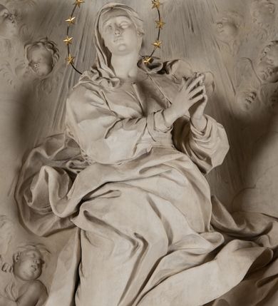 Zdjęcie nr 6: Na niewysokim stopniu prostopadłościenny ołtarz z antepedium, którego dekoracja wykonana w technice marmoryzacji (skaliola) w postaci owalnego pola z wyobrażeniem źródła życia wiecznego (dwa ptaki pijące wodę z fontanny) oraz pęków kwiatów. Nad ołtarzem nastawa z niemal pełnoplastyczną figurą Matki Boskiej Niepokalanej ujęta pilastrami i stojącymi przed nimi marmoryzowanymi kolumnami z kapitelami jońskimi podtrzymującymi szerokie belkowanie zwieńczone naczółkami. W środkowej części belkowania grupa rzeźbiarska z figurą Boga Ojca spoczywającego na obłokach trzymanych przez putta i anioły. Stojąca na obłokach i księżycu Matka Boska ukazana frontalnie, w kontrapoście, z rękami złożonymi do modlitwy. Jej twarz jest modelowana łagodnie, owalna, z długim nosem, otwartymi oczami. Nad głową wieniec z gwiazd. Ubrana jest w długą suknię i rozłożysty płaszcz o skłębionych połach, drapowanych plastycznie. Z tła wyłaniają się putta i uskrzydlone główki aniołów oraz promienie słońca. Postać Boga Ojca siedzącego na chmurach z rozwianymi szatami ukazana frontalnie. Prawą rękę wysuwa do przodu, w lewej trzyma berło. Ołtarz utrzymany w jasnej tonacji kolorystycznej, z elementami z czarnego marmuru i wielobarwnym antepedium w technice marmoryzacji. 