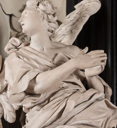 Zdjęcie nr 38: Na niskim postumencie, na rzucie prostokąta z łukiem nadwieszonym od przodu, prostopadłościenny ołtarz z antepedium ujętym szerokimi lizenami z romboidalnymi polami wypełnionymi drobnymi kwiatami, z owalnym polem pośrodku z podłużnymi palmami męczeństwa i bukietami kwiatów wokół. Nad ołtarzem nastawa z obrazem w kształcie stojącego prostokąta z przedstawieniem św. Piotra uwalnianego przez anioła z okowów. Ołtarz jest ujęty ukośnie dostawionymi postumentami z figurami dwóch aniołów flankujących obraz. Anioły ukazane w poruszonych pozach. Lewy stoi w silnym kontrapoście, z prawą nogą opartą na chmurze, z ciałem skierowanym ku środkowi osi ołtarza, z głową odwróconą w kierunku przeciwnym i wysuniętymi przed siebie rękami złożonymi do modlitwy. Jego twarz jest modelowana łagodnie, nos ma długi, usta rozwarte, a włosy skręcone, krótkie. Ubrany w obficie drapowany płaszcz, którego poły układają się w miękkie fałdy, dołem przechodzące między łydkami. Skrzydła ma rozłożyste, modelowane niesymetrycznie, gęsto upierzone. Drugi anioł klęczy na lewej nodze, wspartej na chmurze, zwrócony jest w kierunku obrazu, z prawą ręką przed sobą, a lewą odrzuconą do tyłu. Twarz ma pociągłą, nos wydatny, włosy krótkie, skręcone. Ubrany w długą suknię, drapowaną obficie, odsłaniającą lewe przedramię. Skrzydła rozłożyste, gęsto upierzone. Górna część ramy obrazu z ukośnie wyłamanym gzymsem z podwieszonymi pod nim impostami, podtrzymywanymi przez wyłaniające się z chmur anioły. Gzyms nad obrazem wyłamuje się półkoliście, na nim pośrodku leży anioł trzymający w lewej ręce banderolę ze złoconymi literami nietworzącymi logicznej całości, a prawą ręką wskazujący w kierunku wnętrza kaplicy. U jego boku skłębione chmury z trzema uskrzydlonymi główkami aniołków. Nad bocznymi partiami gzymsu siedzą uskrzydlone, nagie, pulchne aniołki, jeden z rękami złożonymi w geście modlitwy, drugi z rękami uniesionymi i rozłożonymi. Marmoryzacja utrzymana w kolorach brązów, rama i zwieńczenie czarne, dekoracja rzeźbiarska biała. 