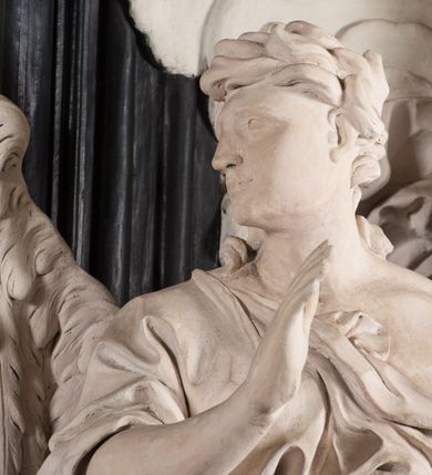 Zdjęcie nr 30: Na niskim postumencie, na rzucie prostokąta z łukiem nadwieszonym od przodu, prostopadłościenny ołtarz z antepedium ujętym szerokimi lizenami z romboidalnymi polami wypełnionymi drobnymi kwiatami, z owalnym polem pośrodku z podłużnymi palmami męczeństwa i bukietami kwiatów wokół. Nad ołtarzem nastawa z obrazem w kształcie stojącego prostokąta z przedstawieniem św. Piotra uwalnianego przez anioła z okowów. Ołtarz jest ujęty ukośnie dostawionymi postumentami z figurami dwóch aniołów flankujących obraz. Anioły ukazane w poruszonych pozach. Lewy stoi w silnym kontrapoście, z prawą nogą opartą na chmurze, z ciałem skierowanym ku środkowi osi ołtarza, z głową odwróconą w kierunku przeciwnym i wysuniętymi przed siebie rękami złożonymi do modlitwy. Jego twarz jest modelowana łagodnie, nos ma długi, usta rozwarte, a włosy skręcone, krótkie. Ubrany w obficie drapowany płaszcz, którego poły układają się w miękkie fałdy, dołem przechodzące między łydkami. Skrzydła ma rozłożyste, modelowane niesymetrycznie, gęsto upierzone. Drugi anioł klęczy na lewej nodze, wspartej na chmurze, zwrócony jest w kierunku obrazu, z prawą ręką przed sobą, a lewą odrzuconą do tyłu. Twarz ma pociągłą, nos wydatny, włosy krótkie, skręcone. Ubrany w długą suknię, drapowaną obficie, odsłaniającą lewe przedramię. Skrzydła rozłożyste, gęsto upierzone. Górna część ramy obrazu z ukośnie wyłamanym gzymsem z podwieszonymi pod nim impostami, podtrzymywanymi przez wyłaniające się z chmur anioły. Gzyms nad obrazem wyłamuje się półkoliście, na nim pośrodku leży anioł trzymający w lewej ręce banderolę ze złoconymi literami nietworzącymi logicznej całości, a prawą ręką wskazujący w kierunku wnętrza kaplicy. U jego boku skłębione chmury z trzema uskrzydlonymi główkami aniołków. Nad bocznymi partiami gzymsu siedzą uskrzydlone, nagie, pulchne aniołki, jeden z rękami złożonymi w geście modlitwy, drugi z rękami uniesionymi i rozłożonymi. Marmoryzacja utrzymana w kolorach brązów, rama i zwieńczenie czarne, dekoracja rzeźbiarska biała. 