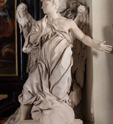 Zdjęcie nr 26: Na niskim postumencie, na rzucie prostokąta z łukiem nadwieszonym od przodu, prostopadłościenny ołtarz z antepedium ujętym szerokimi lizenami z romboidalnymi polami wypełnionymi drobnymi kwiatami, z owalnym polem pośrodku z podłużnymi palmami męczeństwa i bukietami kwiatów wokół. Nad ołtarzem nastawa z obrazem w kształcie stojącego prostokąta z przedstawieniem św. Piotra uwalnianego przez anioła z okowów. Ołtarz jest ujęty ukośnie dostawionymi postumentami z figurami dwóch aniołów flankujących obraz. Anioły ukazane w poruszonych pozach. Lewy stoi w silnym kontrapoście, z prawą nogą opartą na chmurze, z ciałem skierowanym ku środkowi osi ołtarza, z głową odwróconą w kierunku przeciwnym i wysuniętymi przed siebie rękami złożonymi do modlitwy. Jego twarz jest modelowana łagodnie, nos ma długi, usta rozwarte, a włosy skręcone, krótkie. Ubrany w obficie drapowany płaszcz, którego poły układają się w miękkie fałdy, dołem przechodzące między łydkami. Skrzydła ma rozłożyste, modelowane niesymetrycznie, gęsto upierzone. Drugi anioł klęczy na lewej nodze, wspartej na chmurze, zwrócony jest w kierunku obrazu, z prawą ręką przed sobą, a lewą odrzuconą do tyłu. Twarz ma pociągłą, nos wydatny, włosy krótkie, skręcone. Ubrany w długą suknię, drapowaną obficie, odsłaniającą lewe przedramię. Skrzydła rozłożyste, gęsto upierzone. Górna część ramy obrazu z ukośnie wyłamanym gzymsem z podwieszonymi pod nim impostami, podtrzymywanymi przez wyłaniające się z chmur anioły. Gzyms nad obrazem wyłamuje się półkoliście, na nim pośrodku leży anioł trzymający w lewej ręce banderolę ze złoconymi literami nietworzącymi logicznej całości, a prawą ręką wskazujący w kierunku wnętrza kaplicy. U jego boku skłębione chmury z trzema uskrzydlonymi główkami aniołków. Nad bocznymi partiami gzymsu siedzą uskrzydlone, nagie, pulchne aniołki, jeden z rękami złożonymi w geście modlitwy, drugi z rękami uniesionymi i rozłożonymi. Marmoryzacja utrzymana w kolorach brązów, rama i zwieńczenie czarne, dekoracja rzeźbiarska biała. 