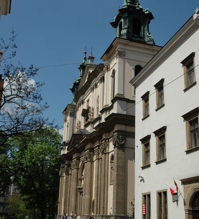 Zdjęcie nr 24: Kościół jest murowany z cegły, z użyciem ciosu kamiennego w partii cokołu i jako okładziny, tynkowany, z kryptami odpowiadającymi rzutowi. Założony jest na rzucie krzyża łacińskiego, z czteroprzęsłową nawą ujętą kaplicami, trójprzęsłowym prezbiterium zamknięty prosto, półtoraprzęsłowymi ramionami nawy poprzecznej, wysuniętymi poza korpus, zamknięte prosto i z kopułą na skrzyżowaniu naw. Przęsło fasady jest ujęte dwiema lokalnościami i dwiema wysuniętymi poza obręb korpusu wieżami z okrągłymi klatkami schodowymi z drewnianymi kręconymi schodami prowadzącymi do pomieszczeń nad lokalnościami. Do prezbiterium przylegają od południowego wschodu zakrystia, od północnego zachodu skarbiec, z składzikami na piętrze. 
Nawa jest artykułowa za pomocą pilastrów kompozytowych, zdwojonych w prezbiterium, transepcie i nawie głównej, zwielokrotniony w krzyżu kościoła, dźwigających wydatne belkowanie. Ściany kaplic są artykułowane za pomocą płytkich, opilastrowanych arkad; mury tarczowe kaplic wydzielone za pomocą gzymsu przełamującego się w narożnikach. Nawa i prezbiterium są sklepione kolebkami na gurtach z lunetami, transept sklepieniem kolebkowym na gurtach, kaplice pseudokopułami na pendentywach (w kaplicy Matki Boskiej i św. Katarzyny kopuły na rzucie elipsy z latarniami), zakrystia i skarbiec sklepieniem krzyżowo-kolebkowo, a przedsionki – nieckowym z lustrem. Okna nawy głównej i prezbiterium w profilowanych obramieniach, prostokątne, zamknięte łukiem segmentowym, okna kaplic są półkoliste. Bęben kopuły rozczłonkowany parami pilastrów kompozytowych, a między nimi rozlokowane naprzemian półkoliście zamknięte nisze i prostokątne okna. Do kościoła prowadzą drzwi wejściowe i para drzwi bocznych, z prezbiterium drzwi wejściowe do skarbca i zakrystii, z zakrystii na dziedziniec przy kościele. 
Fasada poprzedzona schodami, dwukondygnacyjna, dwuwieżowa, w dolnej kondygnacji siedmioosiowa, w górnej trójosiowa z dwiema wyodrębnionymi wieżami. Dolna kondygnacja rozczłonkowana zwojonymi pilastrami i parami kolumn flankujących oś środkową, o kapitelach kompozytowych, podtrzymujących wyłamujące się nad nimi belkowanie z wydatnym gzymsem i attyką, ponad belkowaniem w osi środkowej przerwany przyczółek. Górną kondygnację ujmują pary pilastrów ze stojącymi na ich tle wazonami, dźwigające wyłamujące się nad nimi belkowanie, w części środkowej zwieńczone przyczółkiem, w wieżach – miedzianymi hełmami. 
W części środkowej dolnej kondygnacji znajduje się zamknięta półkoliście wnęka z portalem, ujętym ukośnie dostawionymi pilastrami z konsolami podtrzymującymi naczółki i z tablicą z wklęsłymi bokami, zwieńczoną gzymsem w kształcie łuku nadwieszonego; ponad tablicą znajduje się półkoliste okno. Nad drzwiami bocznymi płaskorzeźbione postacie klęczących aniołów i kwadratowe okna, w wieżach wnęki z figurami św. Bernarda (po lewej) i św. Jana Kantego (po prawej). W części środkowej drugiej kondygnacji umieszczone jest prostokątne okno zamknięte łukiem segmentowym i zwieńczone przerwanym przyczółkiem. W polach bocznych nisze z figurami św. Kazimierza (po lewej) i św. Floriana (po prawej). Ściany boczne wzmocnione szkarpami, podzielone lizenami i pilastrami toskańskimi w dolnej kondygnacji prezbiterium oraz południowo wschodniej i północno zachodniej ścianie transeptu. Prezbiterium i ramiona transeptu zamknięte trójkątnymi szczytami z owalnymi oknami. Tambur kopuły rozczłonkowany lizenami, z oknami zamkniętymi łukami segmentowymi, w profilowanych obramieniach; ośmiopolową kopułę krytą blachą wieńczy latarnia opięta półkolumnami, pomiędzy którymi znajdują się wąskie okna zamknięte półkoliście. Nawę, prezbiterium i transept nakrywa dach siodłowy, nad pozostałymi pomieszczeniami dachy siodłowe, z wyjątkiem środkowych kaplic, w których kopułki wtopione zostały w dach i zwieńczone latarniami.  
