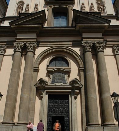 Zdjęcie nr 46: Kościół jest murowany z cegły, z użyciem ciosu kamiennego w partii cokołu i jako okładziny, tynkowany, z kryptami odpowiadającymi rzutowi. Założony jest na rzucie krzyża łacińskiego, z czteroprzęsłową nawą ujętą kaplicami, trójprzęsłowym prezbiterium zamknięty prosto, półtoraprzęsłowymi ramionami nawy poprzecznej, wysuniętymi poza korpus, zamknięte prosto i z kopułą na skrzyżowaniu naw. Przęsło fasady jest ujęte dwiema lokalnościami i dwiema wysuniętymi poza obręb korpusu wieżami z okrągłymi klatkami schodowymi z drewnianymi kręconymi schodami prowadzącymi do pomieszczeń nad lokalnościami. Do prezbiterium przylegają od południowego wschodu zakrystia, od północnego zachodu skarbiec, z składzikami na piętrze. 
Nawa jest artykułowa za pomocą pilastrów kompozytowych, zdwojonych w prezbiterium, transepcie i nawie głównej, zwielokrotniony w krzyżu kościoła, dźwigających wydatne belkowanie. Ściany kaplic są artykułowane za pomocą płytkich, opilastrowanych arkad; mury tarczowe kaplic wydzielone za pomocą gzymsu przełamującego się w narożnikach. Nawa i prezbiterium są sklepione kolebkami na gurtach z lunetami, transept sklepieniem kolebkowym na gurtach, kaplice pseudokopułami na pendentywach (w kaplicy Matki Boskiej i św. Katarzyny kopuły na rzucie elipsy z latarniami), zakrystia i skarbiec sklepieniem krzyżowo-kolebkowo, a przedsionki – nieckowym z lustrem. Okna nawy głównej i prezbiterium w profilowanych obramieniach, prostokątne, zamknięte łukiem segmentowym, okna kaplic są półkoliste. Bęben kopuły rozczłonkowany parami pilastrów kompozytowych, a między nimi rozlokowane naprzemian półkoliście zamknięte nisze i prostokątne okna. Do kościoła prowadzą drzwi wejściowe i para drzwi bocznych, z prezbiterium drzwi wejściowe do skarbca i zakrystii, z zakrystii na dziedziniec przy kościele. 
Fasada poprzedzona schodami, dwukondygnacyjna, dwuwieżowa, w dolnej kondygnacji siedmioosiowa, w górnej trójosiowa z dwiema wyodrębnionymi wieżami. Dolna kondygnacja rozczłonkowana zwojonymi pilastrami i parami kolumn flankujących oś środkową, o kapitelach kompozytowych, podtrzymujących wyłamujące się nad nimi belkowanie z wydatnym gzymsem i attyką, ponad belkowaniem w osi środkowej przerwany przyczółek. Górną kondygnację ujmują pary pilastrów ze stojącymi na ich tle wazonami, dźwigające wyłamujące się nad nimi belkowanie, w części środkowej zwieńczone przyczółkiem, w wieżach – miedzianymi hełmami. 
W części środkowej dolnej kondygnacji znajduje się zamknięta półkoliście wnęka z portalem, ujętym ukośnie dostawionymi pilastrami z konsolami podtrzymującymi naczółki i z tablicą z wklęsłymi bokami, zwieńczoną gzymsem w kształcie łuku nadwieszonego; ponad tablicą znajduje się półkoliste okno. Nad drzwiami bocznymi płaskorzeźbione postacie klęczących aniołów i kwadratowe okna, w wieżach wnęki z figurami św. Bernarda (po lewej) i św. Jana Kantego (po prawej). W części środkowej drugiej kondygnacji umieszczone jest prostokątne okno zamknięte łukiem segmentowym i zwieńczone przerwanym przyczółkiem. W polach bocznych nisze z figurami św. Kazimierza (po lewej) i św. Floriana (po prawej). Ściany boczne wzmocnione szkarpami, podzielone lizenami i pilastrami toskańskimi w dolnej kondygnacji prezbiterium oraz południowo wschodniej i północno zachodniej ścianie transeptu. Prezbiterium i ramiona transeptu zamknięte trójkątnymi szczytami z owalnymi oknami. Tambur kopuły rozczłonkowany lizenami, z oknami zamkniętymi łukami segmentowymi, w profilowanych obramieniach; ośmiopolową kopułę krytą blachą wieńczy latarnia opięta półkolumnami, pomiędzy którymi znajdują się wąskie okna zamknięte półkoliście. Nawę, prezbiterium i transept nakrywa dach siodłowy, nad pozostałymi pomieszczeniami dachy siodłowe, z wyjątkiem środkowych kaplic, w których kopułki wtopione zostały w dach i zwieńczone latarniami.  
