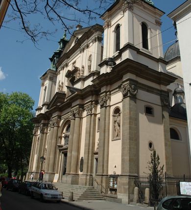 Zdjęcie nr 1: Kościół jest murowany z cegły, z użyciem ciosu kamiennego w partii cokołu i jako okładziny, tynkowany, z kryptami odpowiadającymi rzutowi. Założony jest na rzucie krzyża łacińskiego, z czteroprzęsłową nawą ujętą kaplicami, trójprzęsłowym prezbiterium zamknięty prosto, półtoraprzęsłowymi ramionami nawy poprzecznej, wysuniętymi poza korpus, zamknięte prosto i z kopułą na skrzyżowaniu naw. Przęsło fasady jest ujęte dwiema lokalnościami i dwiema wysuniętymi poza obręb korpusu wieżami z okrągłymi klatkami schodowymi z drewnianymi kręconymi schodami prowadzącymi do pomieszczeń nad lokalnościami. Do prezbiterium przylegają od południowego wschodu zakrystia, od północnego zachodu skarbiec, z składzikami na piętrze. 
Nawa jest artykułowa za pomocą pilastrów kompozytowych, zdwojonych w prezbiterium, transepcie i nawie głównej, zwielokrotniony w krzyżu kościoła, dźwigających wydatne belkowanie. Ściany kaplic są artykułowane za pomocą płytkich, opilastrowanych arkad; mury tarczowe kaplic wydzielone za pomocą gzymsu przełamującego się w narożnikach. Nawa i prezbiterium są sklepione kolebkami na gurtach z lunetami, transept sklepieniem kolebkowym na gurtach, kaplice pseudokopułami na pendentywach (w kaplicy Matki Boskiej i św. Katarzyny kopuły na rzucie elipsy z latarniami), zakrystia i skarbiec sklepieniem krzyżowo-kolebkowo, a przedsionki – nieckowym z lustrem. Okna nawy głównej i prezbiterium w profilowanych obramieniach, prostokątne, zamknięte łukiem segmentowym, okna kaplic są półkoliste. Bęben kopuły rozczłonkowany parami pilastrów kompozytowych, a między nimi rozlokowane naprzemian półkoliście zamknięte nisze i prostokątne okna. Do kościoła prowadzą drzwi wejściowe i para drzwi bocznych, z prezbiterium drzwi wejściowe do skarbca i zakrystii, z zakrystii na dziedziniec przy kościele. 
Fasada poprzedzona schodami, dwukondygnacyjna, dwuwieżowa, w dolnej kondygnacji siedmioosiowa, w górnej trójosiowa z dwiema wyodrębnionymi wieżami. Dolna kondygnacja rozczłonkowana zwojonymi pilastrami i parami kolumn flankujących oś środkową, o kapitelach kompozytowych, podtrzymujących wyłamujące się nad nimi belkowanie z wydatnym gzymsem i attyką, ponad belkowaniem w osi środkowej przerwany przyczółek. Górną kondygnację ujmują pary pilastrów ze stojącymi na ich tle wazonami, dźwigające wyłamujące się nad nimi belkowanie, w części środkowej zwieńczone przyczółkiem, w wieżach – miedzianymi hełmami. 
W części środkowej dolnej kondygnacji znajduje się zamknięta półkoliście wnęka z portalem, ujętym ukośnie dostawionymi pilastrami z konsolami podtrzymującymi naczółki i z tablicą z wklęsłymi bokami, zwieńczoną gzymsem w kształcie łuku nadwieszonego; ponad tablicą znajduje się półkoliste okno. Nad drzwiami bocznymi płaskorzeźbione postacie klęczących aniołów i kwadratowe okna, w wieżach wnęki z figurami św. Bernarda (po lewej) i św. Jana Kantego (po prawej). W części środkowej drugiej kondygnacji umieszczone jest prostokątne okno zamknięte łukiem segmentowym i zwieńczone przerwanym przyczółkiem. W polach bocznych nisze z figurami św. Kazimierza (po lewej) i św. Floriana (po prawej). Ściany boczne wzmocnione szkarpami, podzielone lizenami i pilastrami toskańskimi w dolnej kondygnacji prezbiterium oraz południowo wschodniej i północno zachodniej ścianie transeptu. Prezbiterium i ramiona transeptu zamknięte trójkątnymi szczytami z owalnymi oknami. Tambur kopuły rozczłonkowany lizenami, z oknami zamkniętymi łukami segmentowymi, w profilowanych obramieniach; ośmiopolową kopułę krytą blachą wieńczy latarnia opięta półkolumnami, pomiędzy którymi znajdują się wąskie okna zamknięte półkoliście. Nawę, prezbiterium i transept nakrywa dach siodłowy, nad pozostałymi pomieszczeniami dachy siodłowe, z wyjątkiem środkowych kaplic, w których kopułki wtopione zostały w dach i zwieńczone latarniami.  

