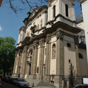 Zdjęcie nr 1: Kościół jest murowany z cegły, z użyciem ciosu kamiennego w partii cokołu i jako okładziny, tynkowany, z kryptami odpowiadającymi rzutowi. Założony jest na rzucie krzyża łacińskiego, z czteroprzęsłową nawą ujętą kaplicami, trójprzęsłowym prezbiterium zamknięty prosto, półtoraprzęsłowymi ramionami nawy poprzecznej, wysuniętymi poza korpus, zamknięte prosto i z kopułą na skrzyżowaniu naw. Przęsło fasady jest ujęte dwiema lokalnościami i dwiema wysuniętymi poza obręb korpusu wieżami z okrągłymi klatkami schodowymi z drewnianymi kręconymi schodami prowadzącymi do pomieszczeń nad lokalnościami. Do prezbiterium przylegają od południowego wschodu zakrystia, od północnego zachodu skarbiec, z składzikami na piętrze. 
Nawa jest artykułowa za pomocą pilastrów kompozytowych, zdwojonych w prezbiterium, transepcie i nawie głównej, zwielokrotniony w krzyżu kościoła, dźwigających wydatne belkowanie. Ściany kaplic są artykułowane za pomocą płytkich, opilastrowanych arkad; mury tarczowe kaplic wydzielone za pomocą gzymsu przełamującego się w narożnikach. Nawa i prezbiterium są sklepione kolebkami na gurtach z lunetami, transept sklepieniem kolebkowym na gurtach, kaplice pseudokopułami na pendentywach (w kaplicy Matki Boskiej i św. Katarzyny kopuły na rzucie elipsy z latarniami), zakrystia i skarbiec sklepieniem krzyżowo-kolebkowo, a przedsionki – nieckowym z lustrem. Okna nawy głównej i prezbiterium w profilowanych obramieniach, prostokątne, zamknięte łukiem segmentowym, okna kaplic są półkoliste. Bęben kopuły rozczłonkowany parami pilastrów kompozytowych, a między nimi rozlokowane naprzemian półkoliście zamknięte nisze i prostokątne okna. Do kościoła prowadzą drzwi wejściowe i para drzwi bocznych, z prezbiterium drzwi wejściowe do skarbca i zakrystii, z zakrystii na dziedziniec przy kościele. 
Fasada poprzedzona schodami, dwukondygnacyjna, dwuwieżowa, w dolnej kondygnacji siedmioosiowa, w górnej trójosiowa z dwiema wyodrębnionymi wieżami. Dolna kondygnacja rozczłonkowana zwojonymi pilastrami i parami kolumn flankujących oś środkową, o kapitelach kompozytowych, podtrzymujących wyłamujące się nad nimi belkowanie z wydatnym gzymsem i attyką, ponad belkowaniem w osi środkowej przerwany przyczółek. Górną kondygnację ujmują pary pilastrów ze stojącymi na ich tle wazonami, dźwigające wyłamujące się nad nimi belkowanie, w części środkowej zwieńczone przyczółkiem, w wieżach – miedzianymi hełmami. 
W części środkowej dolnej kondygnacji znajduje się zamknięta półkoliście wnęka z portalem, ujętym ukośnie dostawionymi pilastrami z konsolami podtrzymującymi naczółki i z tablicą z wklęsłymi bokami, zwieńczoną gzymsem w kształcie łuku nadwieszonego; ponad tablicą znajduje się półkoliste okno. Nad drzwiami bocznymi płaskorzeźbione postacie klęczących aniołów i kwadratowe okna, w wieżach wnęki z figurami św. Bernarda (po lewej) i św. Jana Kantego (po prawej). W części środkowej drugiej kondygnacji umieszczone jest prostokątne okno zamknięte łukiem segmentowym i zwieńczone przerwanym przyczółkiem. W polach bocznych nisze z figurami św. Kazimierza (po lewej) i św. Floriana (po prawej). Ściany boczne wzmocnione szkarpami, podzielone lizenami i pilastrami toskańskimi w dolnej kondygnacji prezbiterium oraz południowo wschodniej i północno zachodniej ścianie transeptu. Prezbiterium i ramiona transeptu zamknięte trójkątnymi szczytami z owalnymi oknami. Tambur kopuły rozczłonkowany lizenami, z oknami zamkniętymi łukami segmentowymi, w profilowanych obramieniach; ośmiopolową kopułę krytą blachą wieńczy latarnia opięta półkolumnami, pomiędzy którymi znajdują się wąskie okna zamknięte półkoliście. Nawę, prezbiterium i transept nakrywa dach siodłowy, nad pozostałymi pomieszczeniami dachy siodłowe, z wyjątkiem środkowych kaplic, w których kopułki wtopione zostały w dach i zwieńczone latarniami.  
