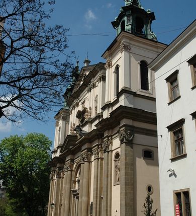 Zdjęcie nr 35: Kościół jest murowany z cegły, z użyciem ciosu kamiennego w partii cokołu i jako okładziny, tynkowany, z kryptami odpowiadającymi rzutowi. Założony jest na rzucie krzyża łacińskiego, z czteroprzęsłową nawą ujętą kaplicami, trójprzęsłowym prezbiterium zamknięty prosto, półtoraprzęsłowymi ramionami nawy poprzecznej, wysuniętymi poza korpus, zamknięte prosto i z kopułą na skrzyżowaniu naw. Przęsło fasady jest ujęte dwiema lokalnościami i dwiema wysuniętymi poza obręb korpusu wieżami z okrągłymi klatkami schodowymi z drewnianymi kręconymi schodami prowadzącymi do pomieszczeń nad lokalnościami. Do prezbiterium przylegają od południowego wschodu zakrystia, od północnego zachodu skarbiec, z składzikami na piętrze. 
Nawa jest artykułowa za pomocą pilastrów kompozytowych, zdwojonych w prezbiterium, transepcie i nawie głównej, zwielokrotniony w krzyżu kościoła, dźwigających wydatne belkowanie. Ściany kaplic są artykułowane za pomocą płytkich, opilastrowanych arkad; mury tarczowe kaplic wydzielone za pomocą gzymsu przełamującego się w narożnikach. Nawa i prezbiterium są sklepione kolebkami na gurtach z lunetami, transept sklepieniem kolebkowym na gurtach, kaplice pseudokopułami na pendentywach (w kaplicy Matki Boskiej i św. Katarzyny kopuły na rzucie elipsy z latarniami), zakrystia i skarbiec sklepieniem krzyżowo-kolebkowo, a przedsionki – nieckowym z lustrem. Okna nawy głównej i prezbiterium w profilowanych obramieniach, prostokątne, zamknięte łukiem segmentowym, okna kaplic są półkoliste. Bęben kopuły rozczłonkowany parami pilastrów kompozytowych, a między nimi rozlokowane naprzemian półkoliście zamknięte nisze i prostokątne okna. Do kościoła prowadzą drzwi wejściowe i para drzwi bocznych, z prezbiterium drzwi wejściowe do skarbca i zakrystii, z zakrystii na dziedziniec przy kościele. 
Fasada poprzedzona schodami, dwukondygnacyjna, dwuwieżowa, w dolnej kondygnacji siedmioosiowa, w górnej trójosiowa z dwiema wyodrębnionymi wieżami. Dolna kondygnacja rozczłonkowana zwojonymi pilastrami i parami kolumn flankujących oś środkową, o kapitelach kompozytowych, podtrzymujących wyłamujące się nad nimi belkowanie z wydatnym gzymsem i attyką, ponad belkowaniem w osi środkowej przerwany przyczółek. Górną kondygnację ujmują pary pilastrów ze stojącymi na ich tle wazonami, dźwigające wyłamujące się nad nimi belkowanie, w części środkowej zwieńczone przyczółkiem, w wieżach – miedzianymi hełmami. 
W części środkowej dolnej kondygnacji znajduje się zamknięta półkoliście wnęka z portalem, ujętym ukośnie dostawionymi pilastrami z konsolami podtrzymującymi naczółki i z tablicą z wklęsłymi bokami, zwieńczoną gzymsem w kształcie łuku nadwieszonego; ponad tablicą znajduje się półkoliste okno. Nad drzwiami bocznymi płaskorzeźbione postacie klęczących aniołów i kwadratowe okna, w wieżach wnęki z figurami św. Bernarda (po lewej) i św. Jana Kantego (po prawej). W części środkowej drugiej kondygnacji umieszczone jest prostokątne okno zamknięte łukiem segmentowym i zwieńczone przerwanym przyczółkiem. W polach bocznych nisze z figurami św. Kazimierza (po lewej) i św. Floriana (po prawej). Ściany boczne wzmocnione szkarpami, podzielone lizenami i pilastrami toskańskimi w dolnej kondygnacji prezbiterium oraz południowo wschodniej i północno zachodniej ścianie transeptu. Prezbiterium i ramiona transeptu zamknięte trójkątnymi szczytami z owalnymi oknami. Tambur kopuły rozczłonkowany lizenami, z oknami zamkniętymi łukami segmentowymi, w profilowanych obramieniach; ośmiopolową kopułę krytą blachą wieńczy latarnia opięta półkolumnami, pomiędzy którymi znajdują się wąskie okna zamknięte półkoliście. Nawę, prezbiterium i transept nakrywa dach siodłowy, nad pozostałymi pomieszczeniami dachy siodłowe, z wyjątkiem środkowych kaplic, w których kopułki wtopione zostały w dach i zwieńczone latarniami.  
