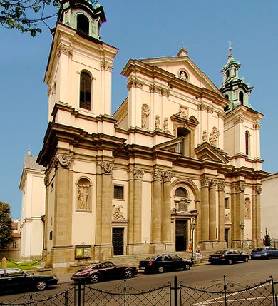 Zdjęcie nr 2: Kościół jest murowany z cegły, z użyciem ciosu kamiennego w partii cokołu i jako okładziny, tynkowany, z kryptami odpowiadającymi rzutowi. Założony jest na rzucie krzyża łacińskiego, z czteroprzęsłową nawą ujętą kaplicami, trójprzęsłowym prezbiterium zamknięty prosto, półtoraprzęsłowymi ramionami nawy poprzecznej, wysuniętymi poza korpus, zamknięte prosto i z kopułą na skrzyżowaniu naw. Przęsło fasady jest ujęte dwiema lokalnościami i dwiema wysuniętymi poza obręb korpusu wieżami z okrągłymi klatkami schodowymi z drewnianymi kręconymi schodami prowadzącymi do pomieszczeń nad lokalnościami. Do prezbiterium przylegają od południowego wschodu zakrystia, od północnego zachodu skarbiec, z składzikami na piętrze. 
Nawa jest artykułowa za pomocą pilastrów kompozytowych, zdwojonych w prezbiterium, transepcie i nawie głównej, zwielokrotniony w krzyżu kościoła, dźwigających wydatne belkowanie. Ściany kaplic są artykułowane za pomocą płytkich, opilastrowanych arkad; mury tarczowe kaplic wydzielone za pomocą gzymsu przełamującego się w narożnikach. Nawa i prezbiterium są sklepione kolebkami na gurtach z lunetami, transept sklepieniem kolebkowym na gurtach, kaplice pseudokopułami na pendentywach (w kaplicy Matki Boskiej i św. Katarzyny kopuły na rzucie elipsy z latarniami), zakrystia i skarbiec sklepieniem krzyżowo-kolebkowo, a przedsionki – nieckowym z lustrem. Okna nawy głównej i prezbiterium w profilowanych obramieniach, prostokątne, zamknięte łukiem segmentowym, okna kaplic są półkoliste. Bęben kopuły rozczłonkowany parami pilastrów kompozytowych, a między nimi rozlokowane naprzemian półkoliście zamknięte nisze i prostokątne okna. Do kościoła prowadzą drzwi wejściowe i para drzwi bocznych, z prezbiterium drzwi wejściowe do skarbca i zakrystii, z zakrystii na dziedziniec przy kościele. 
Fasada poprzedzona schodami, dwukondygnacyjna, dwuwieżowa, w dolnej kondygnacji siedmioosiowa, w górnej trójosiowa z dwiema wyodrębnionymi wieżami. Dolna kondygnacja rozczłonkowana zwojonymi pilastrami i parami kolumn flankujących oś środkową, o kapitelach kompozytowych, podtrzymujących wyłamujące się nad nimi belkowanie z wydatnym gzymsem i attyką, ponad belkowaniem w osi środkowej przerwany przyczółek. Górną kondygnację ujmują pary pilastrów ze stojącymi na ich tle wazonami, dźwigające wyłamujące się nad nimi belkowanie, w części środkowej zwieńczone przyczółkiem, w wieżach – miedzianymi hełmami. 
W części środkowej dolnej kondygnacji znajduje się zamknięta półkoliście wnęka z portalem, ujętym ukośnie dostawionymi pilastrami z konsolami podtrzymującymi naczółki i z tablicą z wklęsłymi bokami, zwieńczoną gzymsem w kształcie łuku nadwieszonego; ponad tablicą znajduje się półkoliste okno. Nad drzwiami bocznymi płaskorzeźbione postacie klęczących aniołów i kwadratowe okna, w wieżach wnęki z figurami św. Bernarda (po lewej) i św. Jana Kantego (po prawej). W części środkowej drugiej kondygnacji umieszczone jest prostokątne okno zamknięte łukiem segmentowym i zwieńczone przerwanym przyczółkiem. W polach bocznych nisze z figurami św. Kazimierza (po lewej) i św. Floriana (po prawej). Ściany boczne wzmocnione szkarpami, podzielone lizenami i pilastrami toskańskimi w dolnej kondygnacji prezbiterium oraz południowo wschodniej i północno zachodniej ścianie transeptu. Prezbiterium i ramiona transeptu zamknięte trójkątnymi szczytami z owalnymi oknami. Tambur kopuły rozczłonkowany lizenami, z oknami zamkniętymi łukami segmentowymi, w profilowanych obramieniach; ośmiopolową kopułę krytą blachą wieńczy latarnia opięta półkolumnami, pomiędzy którymi znajdują się wąskie okna zamknięte półkoliście. Nawę, prezbiterium i transept nakrywa dach siodłowy, nad pozostałymi pomieszczeniami dachy siodłowe, z wyjątkiem środkowych kaplic, w których kopułki wtopione zostały w dach i zwieńczone latarniami.  
