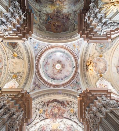 Zdjęcie nr 27: Kościół jest murowany z cegły, z użyciem ciosu kamiennego w partii cokołu i jako okładziny, tynkowany, z kryptami odpowiadającymi rzutowi. Założony jest na rzucie krzyża łacińskiego, z czteroprzęsłową nawą ujętą kaplicami, trójprzęsłowym prezbiterium zamknięty prosto, półtoraprzęsłowymi ramionami nawy poprzecznej, wysuniętymi poza korpus, zamknięte prosto i z kopułą na skrzyżowaniu naw. Przęsło fasady jest ujęte dwiema lokalnościami i dwiema wysuniętymi poza obręb korpusu wieżami z okrągłymi klatkami schodowymi z drewnianymi kręconymi schodami prowadzącymi do pomieszczeń nad lokalnościami. Do prezbiterium przylegają od południowego wschodu zakrystia, od północnego zachodu skarbiec, z składzikami na piętrze. 
Nawa jest artykułowa za pomocą pilastrów kompozytowych, zdwojonych w prezbiterium, transepcie i nawie głównej, zwielokrotniony w krzyżu kościoła, dźwigających wydatne belkowanie. Ściany kaplic są artykułowane za pomocą płytkich, opilastrowanych arkad; mury tarczowe kaplic wydzielone za pomocą gzymsu przełamującego się w narożnikach. Nawa i prezbiterium są sklepione kolebkami na gurtach z lunetami, transept sklepieniem kolebkowym na gurtach, kaplice pseudokopułami na pendentywach (w kaplicy Matki Boskiej i św. Katarzyny kopuły na rzucie elipsy z latarniami), zakrystia i skarbiec sklepieniem krzyżowo-kolebkowo, a przedsionki – nieckowym z lustrem. Okna nawy głównej i prezbiterium w profilowanych obramieniach, prostokątne, zamknięte łukiem segmentowym, okna kaplic są półkoliste. Bęben kopuły rozczłonkowany parami pilastrów kompozytowych, a między nimi rozlokowane naprzemian półkoliście zamknięte nisze i prostokątne okna. Do kościoła prowadzą drzwi wejściowe i para drzwi bocznych, z prezbiterium drzwi wejściowe do skarbca i zakrystii, z zakrystii na dziedziniec przy kościele. 
Fasada poprzedzona schodami, dwukondygnacyjna, dwuwieżowa, w dolnej kondygnacji siedmioosiowa, w górnej trójosiowa z dwiema wyodrębnionymi wieżami. Dolna kondygnacja rozczłonkowana zwojonymi pilastrami i parami kolumn flankujących oś środkową, o kapitelach kompozytowych, podtrzymujących wyłamujące się nad nimi belkowanie z wydatnym gzymsem i attyką, ponad belkowaniem w osi środkowej przerwany przyczółek. Górną kondygnację ujmują pary pilastrów ze stojącymi na ich tle wazonami, dźwigające wyłamujące się nad nimi belkowanie, w części środkowej zwieńczone przyczółkiem, w wieżach – miedzianymi hełmami. 
W części środkowej dolnej kondygnacji znajduje się zamknięta półkoliście wnęka z portalem, ujętym ukośnie dostawionymi pilastrami z konsolami podtrzymującymi naczółki i z tablicą z wklęsłymi bokami, zwieńczoną gzymsem w kształcie łuku nadwieszonego; ponad tablicą znajduje się półkoliste okno. Nad drzwiami bocznymi płaskorzeźbione postacie klęczących aniołów i kwadratowe okna, w wieżach wnęki z figurami św. Bernarda (po lewej) i św. Jana Kantego (po prawej). W części środkowej drugiej kondygnacji umieszczone jest prostokątne okno zamknięte łukiem segmentowym i zwieńczone przerwanym przyczółkiem. W polach bocznych nisze z figurami św. Kazimierza (po lewej) i św. Floriana (po prawej). Ściany boczne wzmocnione szkarpami, podzielone lizenami i pilastrami toskańskimi w dolnej kondygnacji prezbiterium oraz południowo wschodniej i północno zachodniej ścianie transeptu. Prezbiterium i ramiona transeptu zamknięte trójkątnymi szczytami z owalnymi oknami. Tambur kopuły rozczłonkowany lizenami, z oknami zamkniętymi łukami segmentowymi, w profilowanych obramieniach; ośmiopolową kopułę krytą blachą wieńczy latarnia opięta półkolumnami, pomiędzy którymi znajdują się wąskie okna zamknięte półkoliście. Nawę, prezbiterium i transept nakrywa dach siodłowy, nad pozostałymi pomieszczeniami dachy siodłowe, z wyjątkiem środkowych kaplic, w których kopułki wtopione zostały w dach i zwieńczone latarniami.  
