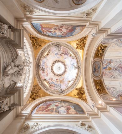 Zdjęcie nr 34: Kościół jest murowany z cegły, z użyciem ciosu kamiennego w partii cokołu i jako okładziny, tynkowany, z kryptami odpowiadającymi rzutowi. Założony jest na rzucie krzyża łacińskiego, z czteroprzęsłową nawą ujętą kaplicami, trójprzęsłowym prezbiterium zamknięty prosto, półtoraprzęsłowymi ramionami nawy poprzecznej, wysuniętymi poza korpus, zamknięte prosto i z kopułą na skrzyżowaniu naw. Przęsło fasady jest ujęte dwiema lokalnościami i dwiema wysuniętymi poza obręb korpusu wieżami z okrągłymi klatkami schodowymi z drewnianymi kręconymi schodami prowadzącymi do pomieszczeń nad lokalnościami. Do prezbiterium przylegają od południowego wschodu zakrystia, od północnego zachodu skarbiec, z składzikami na piętrze. 
Nawa jest artykułowa za pomocą pilastrów kompozytowych, zdwojonych w prezbiterium, transepcie i nawie głównej, zwielokrotniony w krzyżu kościoła, dźwigających wydatne belkowanie. Ściany kaplic są artykułowane za pomocą płytkich, opilastrowanych arkad; mury tarczowe kaplic wydzielone za pomocą gzymsu przełamującego się w narożnikach. Nawa i prezbiterium są sklepione kolebkami na gurtach z lunetami, transept sklepieniem kolebkowym na gurtach, kaplice pseudokopułami na pendentywach (w kaplicy Matki Boskiej i św. Katarzyny kopuły na rzucie elipsy z latarniami), zakrystia i skarbiec sklepieniem krzyżowo-kolebkowo, a przedsionki – nieckowym z lustrem. Okna nawy głównej i prezbiterium w profilowanych obramieniach, prostokątne, zamknięte łukiem segmentowym, okna kaplic są półkoliste. Bęben kopuły rozczłonkowany parami pilastrów kompozytowych, a między nimi rozlokowane naprzemian półkoliście zamknięte nisze i prostokątne okna. Do kościoła prowadzą drzwi wejściowe i para drzwi bocznych, z prezbiterium drzwi wejściowe do skarbca i zakrystii, z zakrystii na dziedziniec przy kościele. 
Fasada poprzedzona schodami, dwukondygnacyjna, dwuwieżowa, w dolnej kondygnacji siedmioosiowa, w górnej trójosiowa z dwiema wyodrębnionymi wieżami. Dolna kondygnacja rozczłonkowana zwojonymi pilastrami i parami kolumn flankujących oś środkową, o kapitelach kompozytowych, podtrzymujących wyłamujące się nad nimi belkowanie z wydatnym gzymsem i attyką, ponad belkowaniem w osi środkowej przerwany przyczółek. Górną kondygnację ujmują pary pilastrów ze stojącymi na ich tle wazonami, dźwigające wyłamujące się nad nimi belkowanie, w części środkowej zwieńczone przyczółkiem, w wieżach – miedzianymi hełmami. 
W części środkowej dolnej kondygnacji znajduje się zamknięta półkoliście wnęka z portalem, ujętym ukośnie dostawionymi pilastrami z konsolami podtrzymującymi naczółki i z tablicą z wklęsłymi bokami, zwieńczoną gzymsem w kształcie łuku nadwieszonego; ponad tablicą znajduje się półkoliste okno. Nad drzwiami bocznymi płaskorzeźbione postacie klęczących aniołów i kwadratowe okna, w wieżach wnęki z figurami św. Bernarda (po lewej) i św. Jana Kantego (po prawej). W części środkowej drugiej kondygnacji umieszczone jest prostokątne okno zamknięte łukiem segmentowym i zwieńczone przerwanym przyczółkiem. W polach bocznych nisze z figurami św. Kazimierza (po lewej) i św. Floriana (po prawej). Ściany boczne wzmocnione szkarpami, podzielone lizenami i pilastrami toskańskimi w dolnej kondygnacji prezbiterium oraz południowo wschodniej i północno zachodniej ścianie transeptu. Prezbiterium i ramiona transeptu zamknięte trójkątnymi szczytami z owalnymi oknami. Tambur kopuły rozczłonkowany lizenami, z oknami zamkniętymi łukami segmentowymi, w profilowanych obramieniach; ośmiopolową kopułę krytą blachą wieńczy latarnia opięta półkolumnami, pomiędzy którymi znajdują się wąskie okna zamknięte półkoliście. Nawę, prezbiterium i transept nakrywa dach siodłowy, nad pozostałymi pomieszczeniami dachy siodłowe, z wyjątkiem środkowych kaplic, w których kopułki wtopione zostały w dach i zwieńczone latarniami.  
