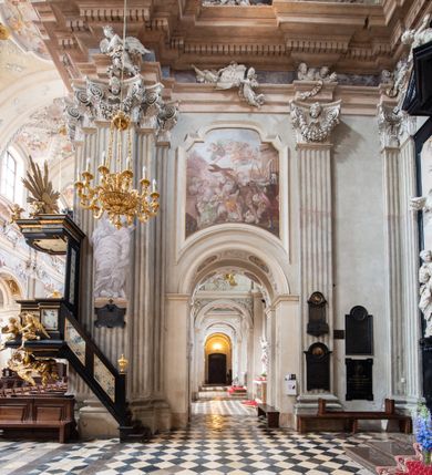 Zdjęcie nr 25: Kościół jest murowany z cegły, z użyciem ciosu kamiennego w partii cokołu i jako okładziny, tynkowany, z kryptami odpowiadającymi rzutowi. Założony jest na rzucie krzyża łacińskiego, z czteroprzęsłową nawą ujętą kaplicami, trójprzęsłowym prezbiterium zamknięty prosto, półtoraprzęsłowymi ramionami nawy poprzecznej, wysuniętymi poza korpus, zamknięte prosto i z kopułą na skrzyżowaniu naw. Przęsło fasady jest ujęte dwiema lokalnościami i dwiema wysuniętymi poza obręb korpusu wieżami z okrągłymi klatkami schodowymi z drewnianymi kręconymi schodami prowadzącymi do pomieszczeń nad lokalnościami. Do prezbiterium przylegają od południowego wschodu zakrystia, od północnego zachodu skarbiec, z składzikami na piętrze. 
Nawa jest artykułowa za pomocą pilastrów kompozytowych, zdwojonych w prezbiterium, transepcie i nawie głównej, zwielokrotniony w krzyżu kościoła, dźwigających wydatne belkowanie. Ściany kaplic są artykułowane za pomocą płytkich, opilastrowanych arkad; mury tarczowe kaplic wydzielone za pomocą gzymsu przełamującego się w narożnikach. Nawa i prezbiterium są sklepione kolebkami na gurtach z lunetami, transept sklepieniem kolebkowym na gurtach, kaplice pseudokopułami na pendentywach (w kaplicy Matki Boskiej i św. Katarzyny kopuły na rzucie elipsy z latarniami), zakrystia i skarbiec sklepieniem krzyżowo-kolebkowo, a przedsionki – nieckowym z lustrem. Okna nawy głównej i prezbiterium w profilowanych obramieniach, prostokątne, zamknięte łukiem segmentowym, okna kaplic są półkoliste. Bęben kopuły rozczłonkowany parami pilastrów kompozytowych, a między nimi rozlokowane naprzemian półkoliście zamknięte nisze i prostokątne okna. Do kościoła prowadzą drzwi wejściowe i para drzwi bocznych, z prezbiterium drzwi wejściowe do skarbca i zakrystii, z zakrystii na dziedziniec przy kościele. 
Fasada poprzedzona schodami, dwukondygnacyjna, dwuwieżowa, w dolnej kondygnacji siedmioosiowa, w górnej trójosiowa z dwiema wyodrębnionymi wieżami. Dolna kondygnacja rozczłonkowana zwojonymi pilastrami i parami kolumn flankujących oś środkową, o kapitelach kompozytowych, podtrzymujących wyłamujące się nad nimi belkowanie z wydatnym gzymsem i attyką, ponad belkowaniem w osi środkowej przerwany przyczółek. Górną kondygnację ujmują pary pilastrów ze stojącymi na ich tle wazonami, dźwigające wyłamujące się nad nimi belkowanie, w części środkowej zwieńczone przyczółkiem, w wieżach – miedzianymi hełmami. 
W części środkowej dolnej kondygnacji znajduje się zamknięta półkoliście wnęka z portalem, ujętym ukośnie dostawionymi pilastrami z konsolami podtrzymującymi naczółki i z tablicą z wklęsłymi bokami, zwieńczoną gzymsem w kształcie łuku nadwieszonego; ponad tablicą znajduje się półkoliste okno. Nad drzwiami bocznymi płaskorzeźbione postacie klęczących aniołów i kwadratowe okna, w wieżach wnęki z figurami św. Bernarda (po lewej) i św. Jana Kantego (po prawej). W części środkowej drugiej kondygnacji umieszczone jest prostokątne okno zamknięte łukiem segmentowym i zwieńczone przerwanym przyczółkiem. W polach bocznych nisze z figurami św. Kazimierza (po lewej) i św. Floriana (po prawej). Ściany boczne wzmocnione szkarpami, podzielone lizenami i pilastrami toskańskimi w dolnej kondygnacji prezbiterium oraz południowo wschodniej i północno zachodniej ścianie transeptu. Prezbiterium i ramiona transeptu zamknięte trójkątnymi szczytami z owalnymi oknami. Tambur kopuły rozczłonkowany lizenami, z oknami zamkniętymi łukami segmentowymi, w profilowanych obramieniach; ośmiopolową kopułę krytą blachą wieńczy latarnia opięta półkolumnami, pomiędzy którymi znajdują się wąskie okna zamknięte półkoliście. Nawę, prezbiterium i transept nakrywa dach siodłowy, nad pozostałymi pomieszczeniami dachy siodłowe, z wyjątkiem środkowych kaplic, w których kopułki wtopione zostały w dach i zwieńczone latarniami.  
