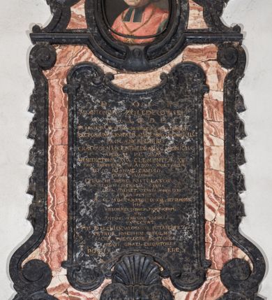 Zdjęcie nr 3: Epitafium w kształcie pionowej płyty, ujętej spływami wolutowymi z kampanulami, z owalnym polem na portret, zwieńczonym profilowanym, falistym gzymsem. U dołu kartusz z herbem własnym (róża przebita strzałą) pod kapeluszem kanonickim, zwieńczony muszlą. Portret ujęty profilowaniem z dwiema zawiniętym na zewnątrz taśmami, przedstawia mężczyznę w popiersiu, w czerwonej pelerynie z zielonymi befkami, z orłem na łańcuchu, z głową ukazaną w trzech czwartych, zwróconą lekko w prawą stronę. Jego twarz jest pełna, o zaczerwienionych policzkach, nos szeroki, oczy otwarte w płytkich oczodołach, spoglądają wprost, usta zamknięte, lekko uśmiechnięte, wyraziście zaznaczone czerwienią. Włosy jasne, zaczesane do tyłu, sięgające szyi, sprawiające wrażenie peruki. Tło nieokreślone, ciemne, w tonacji szarej. Tablica z inskrypcją prostokątna, o zaoblonych, ujętych ceownicami narożach i wyciętych niemal półkoliście krótszych bokach, w niej złocona inskrypcja: &quot;D(EO) O(PTIMO) M(AXIMO) / M. ANTONIUS. ZOŁĘDZIOWSKI / U(TRIUSQUE) J(URIS) S(AGRE) T(HEOLOGIAE) D(OCTOR) P(ROFESSORI) / IN. ACADEMIA. ARCADUM. NORINDUS. CALCEDONIUS. / RECTOR. UNIVERSITATIS. SEPTENNIO. MAGNIFICUS. /  PROCANCELLARUS. / CRACOVIENSIS. CATHEDRALIS. CANONICUS. / APUD. S(UMMI) P(ONTIFICES) MM. / BENEDICTUM. XIV. CLEMENTEM. XIII. / PRO. REFERENDO. III. ALBUM. SANCTORUM. / DIVO. IOANNE. CANTIO. / TRIBUS. LUSTRIS. / FELIX. IN. URBE. POSTULATOR. / PIUS. IUSTUS. LIBERALIS. CARUS. / CUM. VIXISSET. TERRIS. ANNOS. LXXII. / ASTRA. PETIIT. / AE. C. MDCCLXXXIII. IX. KAL(ENDAS) SEPTEMBRIS. / HIC. / RESURRECTIONEM. MORTUORUM. / ET. / VITAM. VENTURI. SECULI. / EXPECTAT. / M(AGNAE) M(AGISTRI) IOSEPHUS. ALOYSIUS. PUTANOWICZ. / PETRUS. IOSEPHUS. RYDULSKI. / SACREA. THEOLOGIE. DOCTORES. / MAESTI. GRATI. EXEQVUTORES. / POSUERE&quot;. 