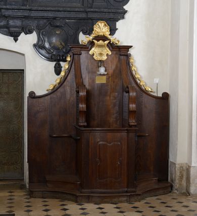 Zdjęcie nr 3: Para konfesjonałów o lekko wybrzuszonym przodzie i wklęsłych bokach, z wysokim zapleckiem ze ściętymi, wklęsłymi bokami, ujętymi spływami wolutowymi. Siedzisko z drzwiczkami ozdobionymi wklęsłą ramą z łukowatymi wcięciami na każdym boku i bokami wyciętymi linią wklęsło-wypukłą, z kratkami. Środkowa część zaplecka zwieńczona profilowanym gzymsem z łukiem nadwieszonymi, w którym znajduje się złocony kartusz ujęty karbowaną taśmą i muszlą palmetową z inskrypcją „KTÓRYCH ODPUŚCICIE / GRZECHY / SĄ IM ODPUSZCZONE / JAN XX. 23”. Nad łukiem muszla palmetowa ujęta wiciami akantu. Wzdłuż spływów wolutowych po bokach złocone kampanule. Do zaplecka, nad siedziskiem zamontowana lampka elektryczna i tabliczka z inskrypcją „W TYM KONFESJONALE SPOWIADAŁ / bł(ogosławiony) Jan Paweł II / ks(iądz) Kardynał Karol Wojtyła / gdy był Pasterzem Kościoła Krakowskiego.”
