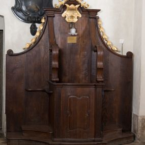 Zdjęcie nr 1: Para konfesjonałów o lekko wybrzuszonym przodzie i wklęsłych bokach, z wysokim zapleckiem ze ściętymi, wklęsłymi bokami, ujętymi spływami wolutowymi. Siedzisko z drzwiczkami ozdobionymi wklęsłą ramą z łukowatymi wcięciami na każdym boku i bokami wyciętymi linią wklęsło-wypukłą, z kratkami. Środkowa część zaplecka zwieńczona profilowanym gzymsem z łukiem nadwieszonymi, w którym znajduje się złocony kartusz ujęty karbowaną taśmą i muszlą palmetową z inskrypcją „KTÓRYCH ODPUŚCICIE / GRZECHY / SĄ IM ODPUSZCZONE / JAN XX. 23”. Nad łukiem muszla palmetowa ujęta wiciami akantu. Wzdłuż spływów wolutowych po bokach złocone kampanule. Do zaplecka, nad siedziskiem zamontowana lampka elektryczna i tabliczka z inskrypcją „W TYM KONFESJONALE SPOWIADAŁ / bł(ogosławiony) Jan Paweł II / ks(iądz) Kardynał Karol Wojtyła / gdy był Pasterzem Kościoła Krakowskiego.”
