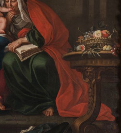 Zdjęcie nr 25: Obraz w kształcie stojącego prostokąta zamkniętego łukiem półkolistym, w złoconej ramie, ozdobionej wieńcem laurowym. W centrum kompozycji ukazana siedząca na fotelu Maria z Jezusem na kolanach i siedząca obok św. Anną w towarzystwie aniołów klęczących u ich stóp lub unoszących się w obłokach. Maria przedstawiona niemal frontalnie, przytrzymuje obiema rękami Jezusa siedzącego na jej lewym kolanie i pochyla głową lekko w lewo. Ubrana jest w różową, rozłożystą suknię i ciemnoniebieski płaszcz oraz brązową chustę na głowie. Jej twarz jest owalna, rysy łagodne, policzki lekko zaróżowione. Nos ma wąski i długi, oczy migdałowate, lekko przymknięte, usta wąskie, pełne, zaznaczone czerwienią. Widoczne spod chusty włosy są proste, opadają na plecy. Jezus siedzi frontalnie, z rozłożonymi nóżkami i rączkami, z których lewą trzyma i całuje św. Anna. Jego twarz jest pełna, policzki lekko zaokrąglone, nos krótki, oczy otwarte, a usta lekko rozwarte i uśmiechnięte, włosy na głowie krótkie, z kręconymi nieznacznie puklami. Dolną część podbrzusza i biodra okrywa biała pielucha. Anna jest ukazana niemal frontalnie, lekko pochylona w kierunku Marii i Jezusa, ubrana w zieloną suknię, czerwony płaszcz i białą chustę okrywającą głowę i szyję. Twarz wykazuje cechy starszej kobiety, z wyraźnymi zmarszczkami, z wyrazistym nosem, zamkniętymi oczami oraz ustami całującymi dłoń Jezusa. Na kolanach trzyma otwartą księgę. Po lewej stronie przy tronie klęczą na chmurach dwa nagie putta, o korpulentnych ciałach, kręconych włosach, z których jedno, na pierwszym planie jest zwrócone w kierunku głównych bohaterów, a drugie z tyłu patrzy na widza. W górnej części kompozycji, na obłoku unoszą się aniołowie, z których jeden, w prawej części kompozycji jest ukazany w całej postaci, w niebieskiej tunice i brązowym płaszczu, z rękami opuszczonymi ku dołowi i złożonymi w geście modlitwy, a głową ujętą z lewego profilu. Środkowy wychyla się zza chmury, okolony zieloną szatą, z lewą ręką złożoną na piersi. Trzeci anioł-putto trzyma pofalowaną kartkę z napisem: „GENERATIONEM EIUS QUIS ENARRABIT”. Po lewej stronie ukazany jest anioł podtrzymujący zieloną kotarę. Pod chmurą, tuż nad głową św. Anny, para uskrzydlonych główek anielskich. W prawej części kompozycji stolik na wolutowych nogach wspartych na lwich łapach i ozdobionych maszkaronami z koszem pełnym owoców oraz leżący na posadzce kosz wiklinowy z niewielką skrzynią i granatową tkaniną z białą podszewką.     

