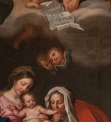 Zdjęcie nr 45: Obraz w kształcie stojącego prostokąta zamkniętego łukiem półkolistym, w złoconej ramie, ozdobionej wieńcem laurowym. W centrum kompozycji ukazana siedząca na fotelu Maria z Jezusem na kolanach i siedząca obok św. Anną w towarzystwie aniołów klęczących u ich stóp lub unoszących się w obłokach. Maria przedstawiona niemal frontalnie, przytrzymuje obiema rękami Jezusa siedzącego na jej lewym kolanie i pochyla głową lekko w lewo. Ubrana jest w różową, rozłożystą suknię i ciemnoniebieski płaszcz oraz brązową chustę na głowie. Jej twarz jest owalna, rysy łagodne, policzki lekko zaróżowione. Nos ma wąski i długi, oczy migdałowate, lekko przymknięte, usta wąskie, pełne, zaznaczone czerwienią. Widoczne spod chusty włosy są proste, opadają na plecy. Jezus siedzi frontalnie, z rozłożonymi nóżkami i rączkami, z których lewą trzyma i całuje św. Anna. Jego twarz jest pełna, policzki lekko zaokrąglone, nos krótki, oczy otwarte, a usta lekko rozwarte i uśmiechnięte, włosy na głowie krótkie, z kręconymi nieznacznie puklami. Dolną część podbrzusza i biodra okrywa biała pielucha. Anna jest ukazana niemal frontalnie, lekko pochylona w kierunku Marii i Jezusa, ubrana w zieloną suknię, czerwony płaszcz i białą chustę okrywającą głowę i szyję. Twarz wykazuje cechy starszej kobiety, z wyraźnymi zmarszczkami, z wyrazistym nosem, zamkniętymi oczami oraz ustami całującymi dłoń Jezusa. Na kolanach trzyma otwartą księgę. Po lewej stronie przy tronie klęczą na chmurach dwa nagie putta, o korpulentnych ciałach, kręconych włosach, z których jedno, na pierwszym planie jest zwrócone w kierunku głównych bohaterów, a drugie z tyłu patrzy na widza. W górnej części kompozycji, na obłoku unoszą się aniołowie, z których jeden, w prawej części kompozycji jest ukazany w całej postaci, w niebieskiej tunice i brązowym płaszczu, z rękami opuszczonymi ku dołowi i złożonymi w geście modlitwy, a głową ujętą z lewego profilu. Środkowy wychyla się zza chmury, okolony zieloną szatą, z lewą ręką złożoną na piersi. Trzeci anioł-putto trzyma pofalowaną kartkę z napisem: „GENERATIONEM EIUS QUIS ENARRABIT”. Po lewej stronie ukazany jest anioł podtrzymujący zieloną kotarę. Pod chmurą, tuż nad głową św. Anny, para uskrzydlonych główek anielskich. W prawej części kompozycji stolik na wolutowych nogach wspartych na lwich łapach i ozdobionych maszkaronami z koszem pełnym owoców oraz leżący na posadzce kosz wiklinowy z niewielką skrzynią i granatową tkaniną z białą podszewką.     

