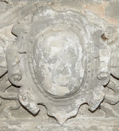 Zdjęcie nr 1: Fragment dekoracji wieńczącej nagrobek Joachima Lubomirskiego. W centrum kartusz z godłem herbu Drużyna zdobiony perełkowaniem i ornamentem rollwerkowym. Flankują go spływy wolutowe uzupełnione wstążkami. 