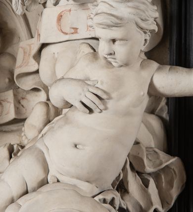 Zdjęcie nr 4: Na trójstopniowej podstawie osadzona prostopadłościenna mensa ołtarza ujęta lekko wybrzuszającymi się postumentami. Antepedium wykonane w technice marmoryzacji (skaliola) z owalnym polem pośrodku, z wyobrażeniem leżącego nagiego Dzieciątka Jezus z krzyżykiem w lewej dłoni i pierścieniem z krzyżem w prawej, pozostałe naroża wypełnione bukietami kwiatów. Na osi mensy nastawa w formie profilowanej ramy prostokątnej zamkniętej łukiem wklęsło-wypukłym, nadwieszonym, wypełnionej płaskorzeźbą z postacią św. Katarzyny. Święta ukazana w trzech czwartych, w pozycji klęczącej, na chmurach, z rękami złożonymi na piersi, z głową lekko odchyloną w głąb kompozycji. Jej twarz jest owalna, o pełnych policzkach, ze smukłym nosem, głębokimi oczodołami i otwartymi ustami. Na głowie włosy modelowane sumarycznie, długie, opadające na plecy oraz korona otwarta. Święta jest ubrana w długą suknię i obficie fałdowany płaszcz. Za jej plecami widoczny fragment koła – atrybutu jej męczeństwa, z przodu wyłaniające się płaskorzeźbione putta, z których jedno trzyma gałąź palmy. W górnej części kompozycji modelowane w płytkim reliefie chmury z widocznymi między nimi promieniami oraz uskrzydlone główki aniołków. Po bokach kolumny osadzone na bazach, ścięte w połowie wysokości ramy, zakończone skłębionymi obłokami chmur i siedzącymi na nich aniołkami. Lewy ukazany w pozycji półleżącej, z prawą ręką na piersi, a lewą wyciągniętą w kierunku osi ołtarza, z głową skierowaną w jego prawą stronę. Anioł po przeciwnej stronie siedzi na obłoku okrakiem i trzyma w ręku palmę męczeństwa. W tle obu aniołów płaskorzeźbione grupy puttów z banderolami z nieczytelnymi inskrypcjami. Nastawę wieńczy gloria promienista, której promienie wchodzą w partię okna, z siedzącą na obłokach postacią małego Jezusa z kulą ziemską przy boku i z prawą ręką uniesioną w geście błogosławieństwa, ubranego w rozwiany na plecach płaszcz. Kompozycję uzupełniają płaskorzeźbione grupy uskrzydlonych aniołków. Ołtarz z elementami czarnego i białego marmuru, barwnej marmoryzacji i białego, częściowo złoconego stiuku. 