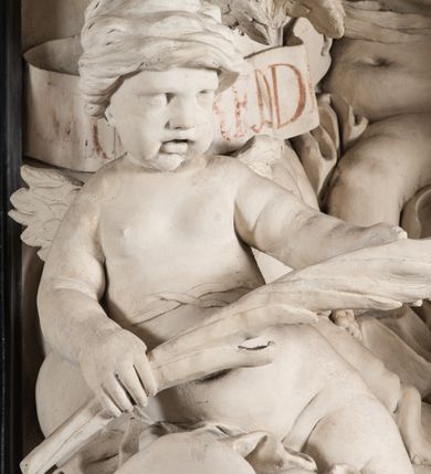 Zdjęcie nr 9: Na trójstopniowej podstawie osadzona prostopadłościenna mensa ołtarza ujęta lekko wybrzuszającymi się postumentami. Antepedium wykonane w technice marmoryzacji (skaliola) z owalnym polem pośrodku, z wyobrażeniem leżącego nagiego Dzieciątka Jezus z krzyżykiem w lewej dłoni i pierścieniem z krzyżem w prawej, pozostałe naroża wypełnione bukietami kwiatów. Na osi mensy nastawa w formie profilowanej ramy prostokątnej zamkniętej łukiem wklęsło-wypukłym, nadwieszonym, wypełnionej płaskorzeźbą z postacią św. Katarzyny. Święta ukazana w trzech czwartych, w pozycji klęczącej, na chmurach, z rękami złożonymi na piersi, z głową lekko odchyloną w głąb kompozycji. Jej twarz jest owalna, o pełnych policzkach, ze smukłym nosem, głębokimi oczodołami i otwartymi ustami. Na głowie włosy modelowane sumarycznie, długie, opadające na plecy oraz korona otwarta. Święta jest ubrana w długą suknię i obficie fałdowany płaszcz. Za jej plecami widoczny fragment koła – atrybutu jej męczeństwa, z przodu wyłaniające się płaskorzeźbione putta, z których jedno trzyma gałąź palmy. W górnej części kompozycji modelowane w płytkim reliefie chmury z widocznymi między nimi promieniami oraz uskrzydlone główki aniołków. Po bokach kolumny osadzone na bazach, ścięte w połowie wysokości ramy, zakończone skłębionymi obłokami chmur i siedzącymi na nich aniołkami. Lewy ukazany w pozycji półleżącej, z prawą ręką na piersi, a lewą wyciągniętą w kierunku osi ołtarza, z głową skierowaną w jego prawą stronę. Anioł po przeciwnej stronie siedzi na obłoku okrakiem i trzyma w ręku palmę męczeństwa. W tle obu aniołów płaskorzeźbione grupy puttów z banderolami z nieczytelnymi inskrypcjami. Nastawę wieńczy gloria promienista, której promienie wchodzą w partię okna, z siedzącą na obłokach postacią małego Jezusa z kulą ziemską przy boku i z prawą ręką uniesioną w geście błogosławieństwa, ubranego w rozwiany na plecach płaszcz. Kompozycję uzupełniają płaskorzeźbione grupy uskrzydlonych aniołków. Ołtarz z elementami czarnego i białego marmuru, barwnej marmoryzacji i białego, częściowo złoconego stiuku. 