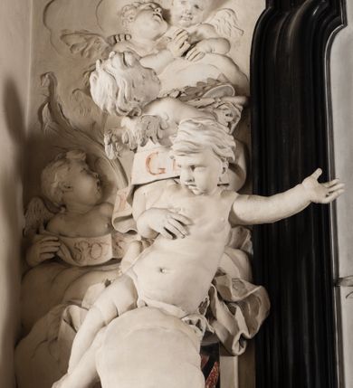 Zdjęcie nr 18: Na trójstopniowej podstawie osadzona prostopadłościenna mensa ołtarza ujęta lekko wybrzuszającymi się postumentami. Antepedium wykonane w technice marmoryzacji (skaliola) z owalnym polem pośrodku, z wyobrażeniem leżącego nagiego Dzieciątka Jezus z krzyżykiem w lewej dłoni i pierścieniem z krzyżem w prawej, pozostałe naroża wypełnione bukietami kwiatów. Na osi mensy nastawa w formie profilowanej ramy prostokątnej zamkniętej łukiem wklęsło-wypukłym, nadwieszonym, wypełnionej płaskorzeźbą z postacią św. Katarzyny. Święta ukazana w trzech czwartych, w pozycji klęczącej, na chmurach, z rękami złożonymi na piersi, z głową lekko odchyloną w głąb kompozycji. Jej twarz jest owalna, o pełnych policzkach, ze smukłym nosem, głębokimi oczodołami i otwartymi ustami. Na głowie włosy modelowane sumarycznie, długie, opadające na plecy oraz korona otwarta. Święta jest ubrana w długą suknię i obficie fałdowany płaszcz. Za jej plecami widoczny fragment koła – atrybutu jej męczeństwa, z przodu wyłaniające się płaskorzeźbione putta, z których jedno trzyma gałąź palmy. W górnej części kompozycji modelowane w płytkim reliefie chmury z widocznymi między nimi promieniami oraz uskrzydlone główki aniołków. Po bokach kolumny osadzone na bazach, ścięte w połowie wysokości ramy, zakończone skłębionymi obłokami chmur i siedzącymi na nich aniołkami. Lewy ukazany w pozycji półleżącej, z prawą ręką na piersi, a lewą wyciągniętą w kierunku osi ołtarza, z głową skierowaną w jego prawą stronę. Anioł po przeciwnej stronie siedzi na obłoku okrakiem i trzyma w ręku palmę męczeństwa. W tle obu aniołów płaskorzeźbione grupy puttów z banderolami z nieczytelnymi inskrypcjami. Nastawę wieńczy gloria promienista, której promienie wchodzą w partię okna, z siedzącą na obłokach postacią małego Jezusa z kulą ziemską przy boku i z prawą ręką uniesioną w geście błogosławieństwa, ubranego w rozwiany na plecach płaszcz. Kompozycję uzupełniają płaskorzeźbione grupy uskrzydlonych aniołków. Ołtarz z elementami czarnego i białego marmuru, barwnej marmoryzacji i białego, częściowo złoconego stiuku. 