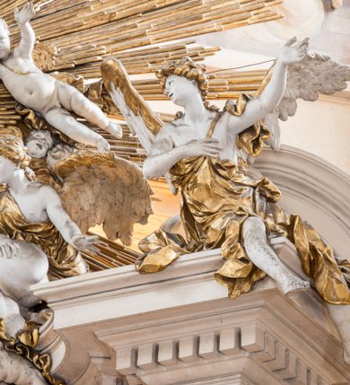 Zdjęcie nr 3: Zasadniczy ołtarz jest prostopadłościenny, z antepedium w technice skalioli, z owalnym polem, w którym znajduje się medalion obwiedziony kwiatami. Wydzielone wokół niego geometryczne pola pokryte są białą i czerwoną marmoryzacją. Za ołtarzem znajduje się monumentalna nastawa, składająca się z podwójnych cokołów, dwóch tylnych, ustawionych równolegle do prezbiterium, dwóch przednich ustawionych ukośnie, na których stoją osadzone na tle pilastrów kolumny o spiralnych trzonach. Po bokach kolumn unoszące się na chmurach uskrzydlone anioły w miękko modelowanych szatach. Trzony kolumn ozdobione wijącą się wokół nich wicią roślinną, ich kapitele w porządku kompozytowym podtrzymują belkowanie. Nad zewnętrznymi kolumnami unoszą się faliste naczółki, zaś nad wewnętrznymi siedzące anioły. Nad ołtarzem posadowiono dużych rozmiarów glorię promienistą z grupą aniołów i puttów. Pośrodku otwarta księga trzymana przez anioły z napisem: LIBER GENERATIONIS IESV CHRISTI. W polu środkowym nisza na obraz w kształcie prostokąta zamkniętego półkoliście, obwiedzionego rzeźbioną ramą z motywem liści lauru; na obrazie przedstawiona św. Anna Samotrzeć. Ołtarz flankują wsunięte do przodu figury św. Wojciecha i św. Stanisława, stojące na dostawionych do ścian bocznych prezbiterium cokołach, wybrzuszających się w górnej części. 