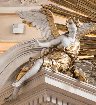 Zdjęcie nr 4: Zasadniczy ołtarz jest prostopadłościenny, z antepedium w technice skalioli, z owalnym polem, w którym znajduje się medalion obwiedziony kwiatami. Wydzielone wokół niego geometryczne pola pokryte są białą i czerwoną marmoryzacją. Za ołtarzem znajduje się monumentalna nastawa, składająca się z podwójnych cokołów, dwóch tylnych, ustawionych równolegle do prezbiterium, dwóch przednich ustawionych ukośnie, na których stoją osadzone na tle pilastrów kolumny o spiralnych trzonach. Po bokach kolumn unoszące się na chmurach uskrzydlone anioły w miękko modelowanych szatach. Trzony kolumn ozdobione wijącą się wokół nich wicią roślinną, ich kapitele w porządku kompozytowym podtrzymują belkowanie. Nad zewnętrznymi kolumnami unoszą się faliste naczółki, zaś nad wewnętrznymi siedzące anioły. Nad ołtarzem posadowiono dużych rozmiarów glorię promienistą z grupą aniołów i puttów. Pośrodku otwarta księga trzymana przez anioły z napisem: LIBER GENERATIONIS IESV CHRISTI. W polu środkowym nisza na obraz w kształcie prostokąta zamkniętego półkoliście, obwiedzionego rzeźbioną ramą z motywem liści lauru; na obrazie przedstawiona św. Anna Samotrzeć. Ołtarz flankują wsunięte do przodu figury św. Wojciecha i św. Stanisława, stojące na dostawionych do ścian bocznych prezbiterium cokołach, wybrzuszających się w górnej części. 