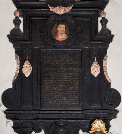 Zdjęcie nr 1: Epitafium w formie stojącego prostokąta wsparte na profilowanym gzymsie z konsolami i podwieszonym pod nim fartuchem z kartuszem z herbem Uniwersytetu Jagiellońskiego, ujęte pilastrami podtrzymującymi przełamujący się w kwadrat gzyms, zwieńczony falistym, przerwanym przyczółkiem z krzyżem pośrodku. Pilastry z kapitelami w formie maszkaronów, trzymających w ustach kiść girland owocowych są ujęte od zewnątrz spływami wolutowymi, od wewnątrz ulistnionymi wydłużonymi wolutami. Pośrodku, w górnej wyłamanej części owalny portret zmarłego w kartuszu "D(EO) O(PTIMO) M(AXIMO) PIIS MANIBUS / / PERILLUSTRIS OLIM ET REVERENDISSIMI DOMINI / M(AGISTRI) ANDREAE KRVPECKI / I(URIS) V(TRIUSQUE) D(OCTOR) ET P(HILOSOPHIAE) CANONICI CRACOVIENSIS PRAEPOSITI / PREMIICOVIENSIS SENIORIS PATRIS ET PROCANCELLARII / UNIVERSITATIS CRAC(OVIENSIS) / QUEM / CANDOR ANIMI AMABILEM ERUDITIO CONSPICUUM HONOR / ILLUSTREM VIRTUS ETIAM POST FATA SUPERSTITEM FECIT / HIC OLIM / IN CALVO MONTE. MOX IN LUBRANSCIANA ACADEMIA / PHI(LOSOPHI)AE PROFESSOR POSTEA DIRECTOR PARTEM SUI MELI/ORIS AEVI GLORIOSE CONSUMPSIT. / IUDEX CONSISTORII CRAC(OVIENSIS) SURROGATUS IUSTITIAM IN/ TEMERATE COLUIT, STUDII GENERALIS ALMAE UNI/VERSITATIS CRAC(OVIENSIS) DIFFICILIMO TEMPORE SEXDECI/ES RECTOR PRO IURIBUS EIUS INDEFESSUS CERTAVIT / COLLEGII IURIDICI INSIGNIS BENEFACTOR SED MAXIME HUIUS BASILICAE QUAM CUPRO INGENTI SU(M)PTU / PENE TOTAM TEXIT ARGENTEA SUPELLECTILI PRETIOSE / ORNAVIT IPSE MORIBUS COMITATE ET VITA ORNATISSIMUS / TANDEM DIERUM ET MERITORUM PLENUS CHRI/STIANE OBIIT ANNO SALUTIS 1.  7. 25 DIE 25 / APRILIS AETATIS SUAE 82. IN ECCLESIA CATHE/DRALIS CRACO(OVIENSIS) EXPECTAT. DONEC VENIAT IMMU/TATIO SUA IN HAC EIUS MEMORIAE HOC MONU/MENTUM EXECUTORES TESTAMENTI POSUERUNT".