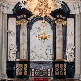 Zdjęcie nr 1: Ołtarz ustawiony na trójstopniowym podeście, prostopadłościenny, z antepedium z dekoracją w technice skaliola z pól geometrycznych dzielonych listwami i wypełniony drobnymi, wielobarwnymi kwiatkami. Za ołtarzem monumentalna nastawa utworzona z pilastrów i ukośnie ustawionych filarów stojących na wysokich postumentach. Ich trzony są kanelowane, a kapitele utworzone z jońskich wolut i przewiązanych taśmą lilijek. Nad kapitelami wznosi się belkowanie, nad zewnętrznymi pilastrami zwieńczone falistymi naczółkami, nad wewnętrznymi grupami uskrzydlonych puttów. Pośrodku znajduje się prostokątna wnęka zakończona łukiem półkolistym, nadwieszonym, w profilowanej ramie. W niej stiukowy relief przedstawiający Chwałę Krzyża Świętego adorowanego przez Matkę Boską z martwym Chrystusem spoczywającym na jej kolanach oraz przez św. Jana Ewangelistę odwróconego do widza plecami. Maria ukazana frontalnie, ubrana w rozłożystą suknię i  płaszcz zarzucony na głowę, z prawą ręką dotykająca głowy Jezusa, z lewą wyciągniętą do przodu. Jan przedstawiony w wykroku, z rękami wysuniętymi przed siebie, ubrany w suknię i płaszcz odkrywający lewy bark. Za Chrystusem ukazany anioł trzymający jego rękę. Nad nimi grupa aniołów unoszących krzyż. Ponad wnęką widnieje promienista, złocona gloria, z postacią Boga Ojca zasiadającego w chmurach, z gołębicą Ducha Świętego, puttami i główkami aniołów. Po bokach stoją figury św. Weroniki i św. Longina. Święta jest ubrana w długą, ekspresyjnie marszczoną suknię, w rękach trzyma rozłożoną chustę z twarzą Chrystusa. Longin jest przestawiony w zbroi rzymskiego legionisty, z długim, efektownie formowanym płaszczem, z lanca w prawej dłoni. 
