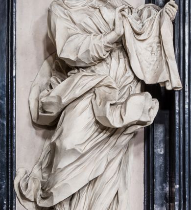 Zdjęcie nr 5: Ołtarz ustawiony na trójstopniowym podeście, prostopadłościenny, z antepedium z dekoracją w technice skaliola z pól geometrycznych dzielonych listwami i wypełniony drobnymi, wielobarwnymi kwiatkami. Za ołtarzem monumentalna nastawa utworzona z pilastrów i ukośnie ustawionych filarów stojących na wysokich postumentach. Ich trzony są kanelowane, a kapitele utworzone z jońskich wolut i przewiązanych taśmą lilijek. Nad kapitelami wznosi się belkowanie, nad zewnętrznymi pilastrami zwieńczone falistymi naczółkami, nad wewnętrznymi grupami uskrzydlonych puttów. Pośrodku znajduje się prostokątna wnęka zakończona łukiem półkolistym, nadwieszonym, w profilowanej ramie. W niej stiukowy relief przedstawiający Chwałę Krzyża Świętego adorowanego przez Matkę Boską z martwym Chrystusem spoczywającym na jej kolanach oraz przez św. Jana Ewangelistę odwróconego do widza plecami. Maria ukazana frontalnie, ubrana w rozłożystą suknię i  płaszcz zarzucony na głowę, z prawą ręką dotykająca głowy Jezusa, z lewą wyciągniętą do przodu. Jan przedstawiony w wykroku, z rękami wysuniętymi przed siebie, ubrany w suknię i płaszcz odkrywający lewy bark. Za Chrystusem ukazany anioł trzymający jego rękę. Nad nimi grupa aniołów unoszących krzyż. Ponad wnęką widnieje promienista, złocona gloria, z postacią Boga Ojca zasiadającego w chmurach, z gołębicą Ducha Świętego, puttami i główkami aniołów. Po bokach stoją figury św. Weroniki i św. Longina. Święta jest ubrana w długą, ekspresyjnie marszczoną suknię, w rękach trzyma rozłożoną chustę z twarzą Chrystusa. Longin jest przestawiony w zbroi rzymskiego legionisty, z długim, efektownie formowanym płaszczem, z lanca w prawej dłoni. 
