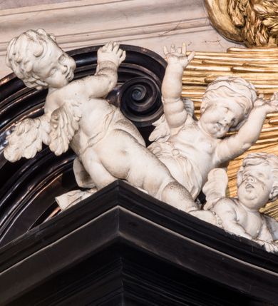 Zdjęcie nr 17: Ołtarz ustawiony na trójstopniowym podeście, prostopadłościenny, z antepedium z dekoracją w technice skaliola z pól geometrycznych dzielonych listwami i wypełniony drobnymi, wielobarwnymi kwiatkami. Za ołtarzem monumentalna nastawa utworzona z pilastrów i ukośnie ustawionych filarów stojących na wysokich postumentach. Ich trzony są kanelowane, a kapitele utworzone z jońskich wolut i przewiązanych taśmą lilijek. Nad kapitelami wznosi się belkowanie, nad zewnętrznymi pilastrami zwieńczone falistymi naczółkami, nad wewnętrznymi grupami uskrzydlonych puttów. Pośrodku znajduje się prostokątna wnęka zakończona łukiem półkolistym, nadwieszonym, w profilowanej ramie. W niej stiukowy relief przedstawiający Chwałę Krzyża Świętego adorowanego przez Matkę Boską z martwym Chrystusem spoczywającym na jej kolanach oraz przez św. Jana Ewangelistę odwróconego do widza plecami. Maria ukazana frontalnie, ubrana w rozłożystą suknię i  płaszcz zarzucony na głowę, z prawą ręką dotykająca głowy Jezusa, z lewą wyciągniętą do przodu. Jan przedstawiony w wykroku, z rękami wysuniętymi przed siebie, ubrany w suknię i płaszcz odkrywający lewy bark. Za Chrystusem ukazany anioł trzymający jego rękę. Nad nimi grupa aniołów unoszących krzyż. Ponad wnęką widnieje promienista, złocona gloria, z postacią Boga Ojca zasiadającego w chmurach, z gołębicą Ducha Świętego, puttami i główkami aniołów. Po bokach stoją figury św. Weroniki i św. Longina. Święta jest ubrana w długą, ekspresyjnie marszczoną suknię, w rękach trzyma rozłożoną chustę z twarzą Chrystusa. Longin jest przestawiony w zbroi rzymskiego legionisty, z długim, efektownie formowanym płaszczem, z lanca w prawej dłoni. 
